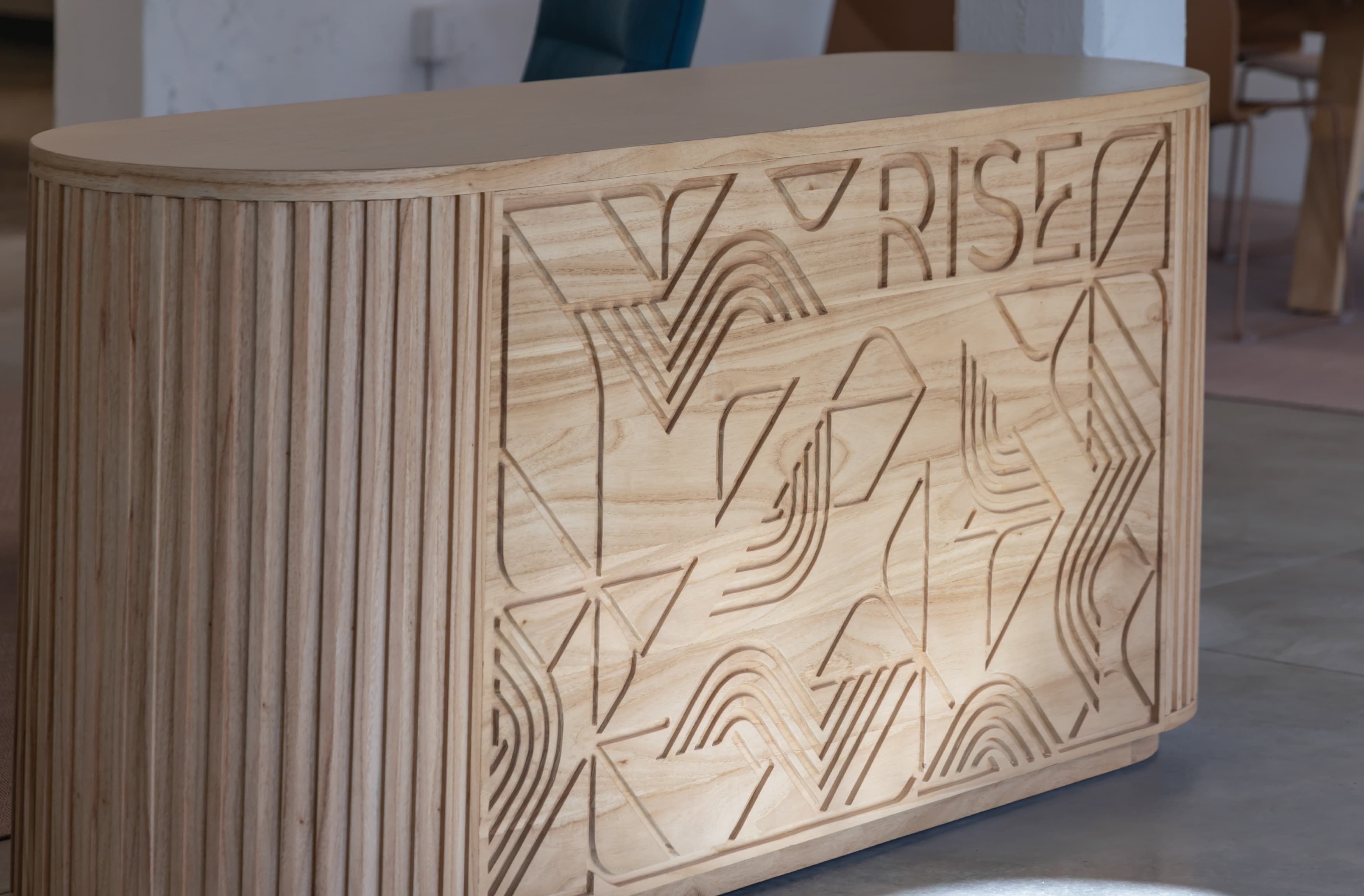 Image of the custom front desk with wooden carved facade, with the Atherton Rise patterning and logo applied, by RSM Design. 