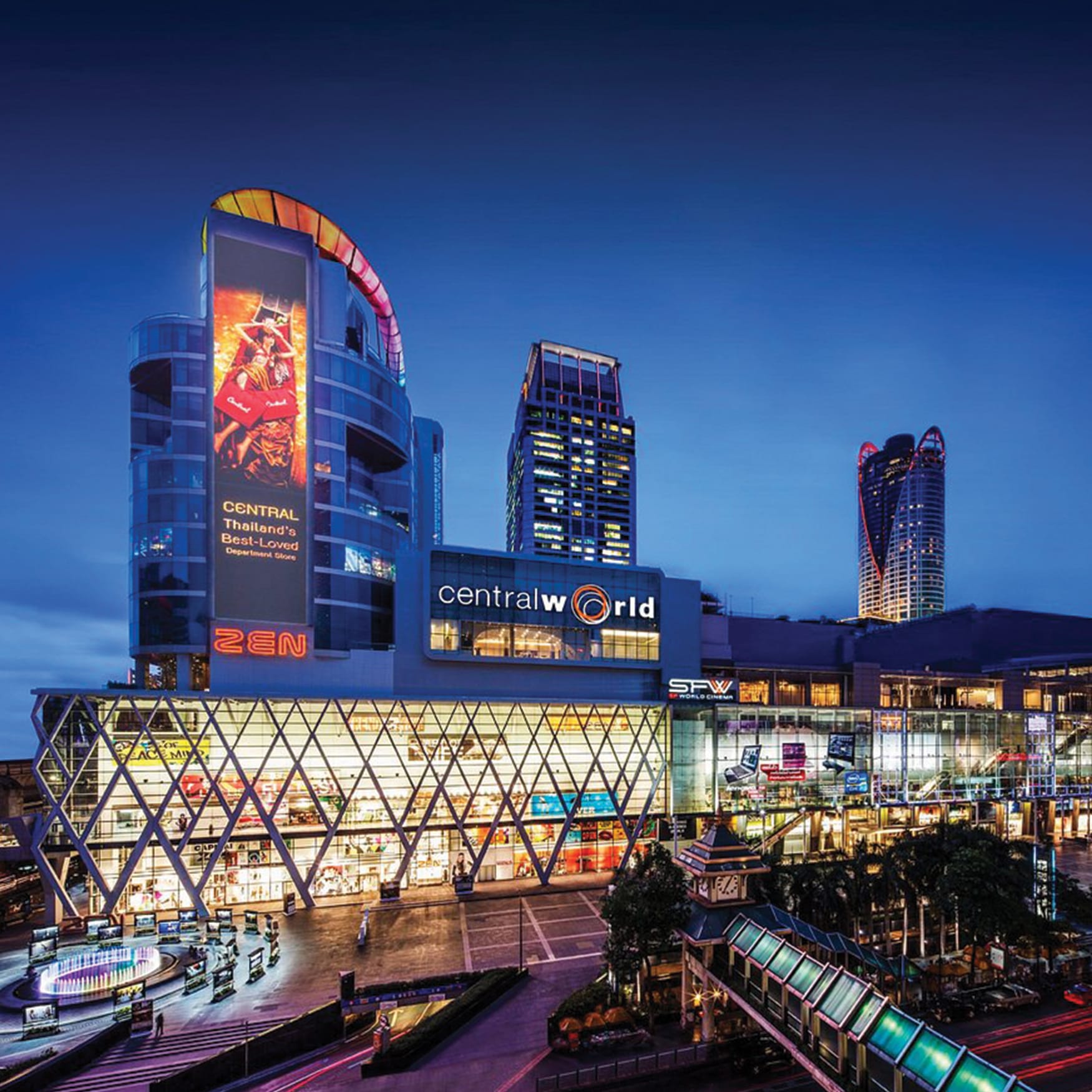 Illuminated exterior view of the CentralWorld shopping complex at night in Bangkok, Thailand, featuring large digital displays and modern geometric facade.