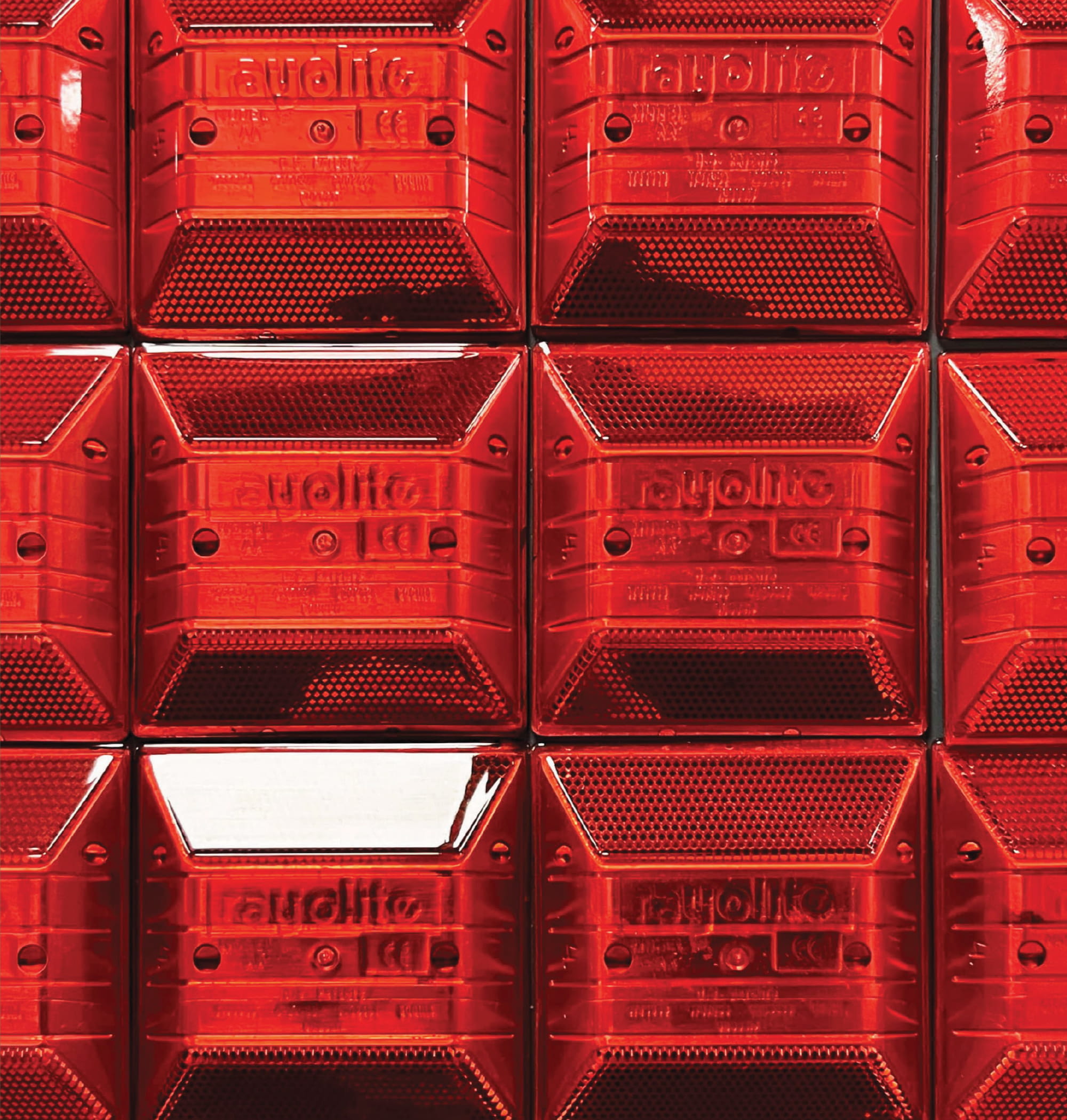 Close-up of modular red acrylic vehicle lights, highlighting materiality and craftsmanship in environmental graphic design, supporting experiential design, brand storytelling, and placemaking within corporate and media workplace environments.