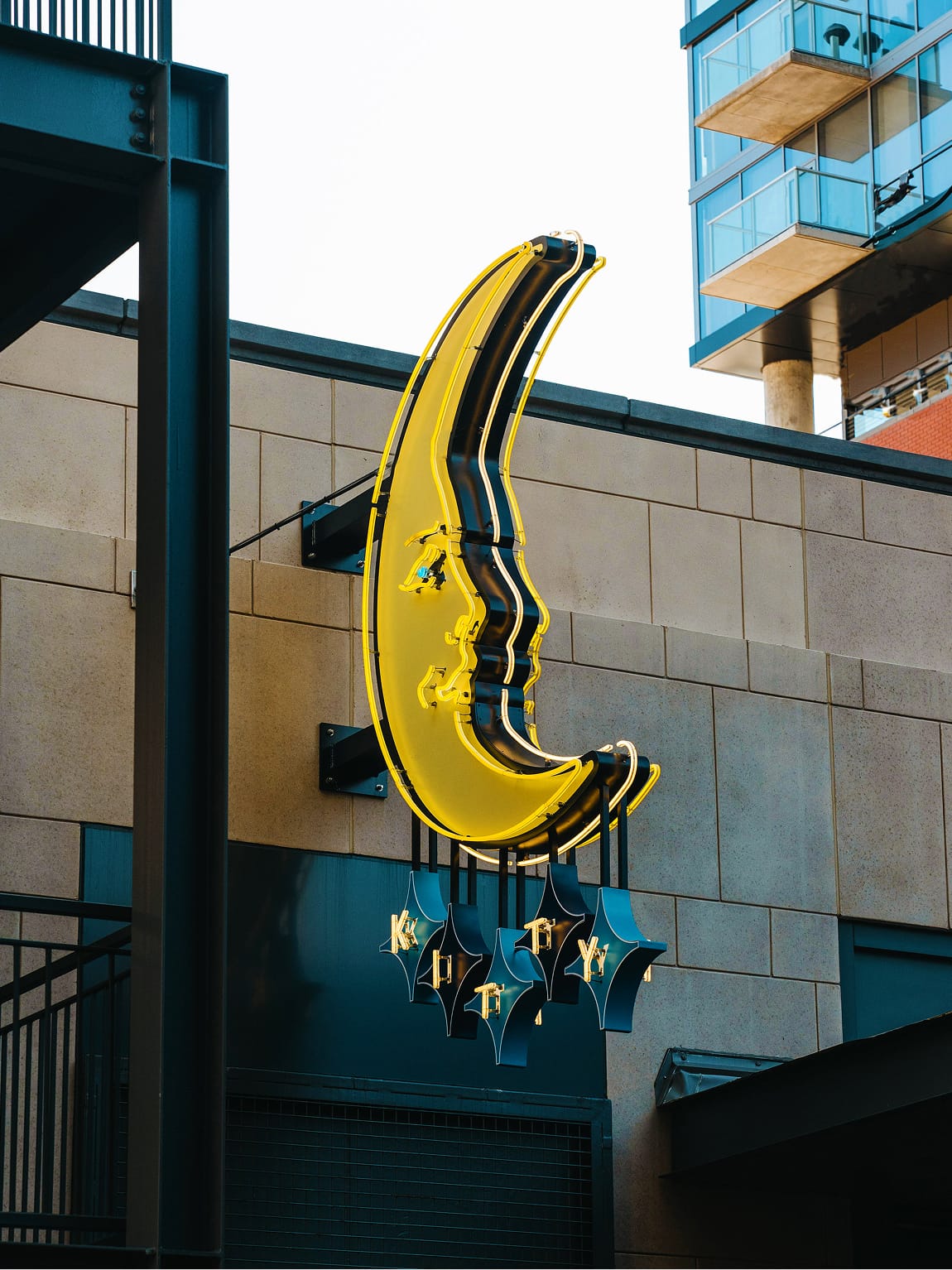 Neon crescent blade sign at Fifth + Broadway, adding a bold and playful visual landmark within the district’s urban streetscape.