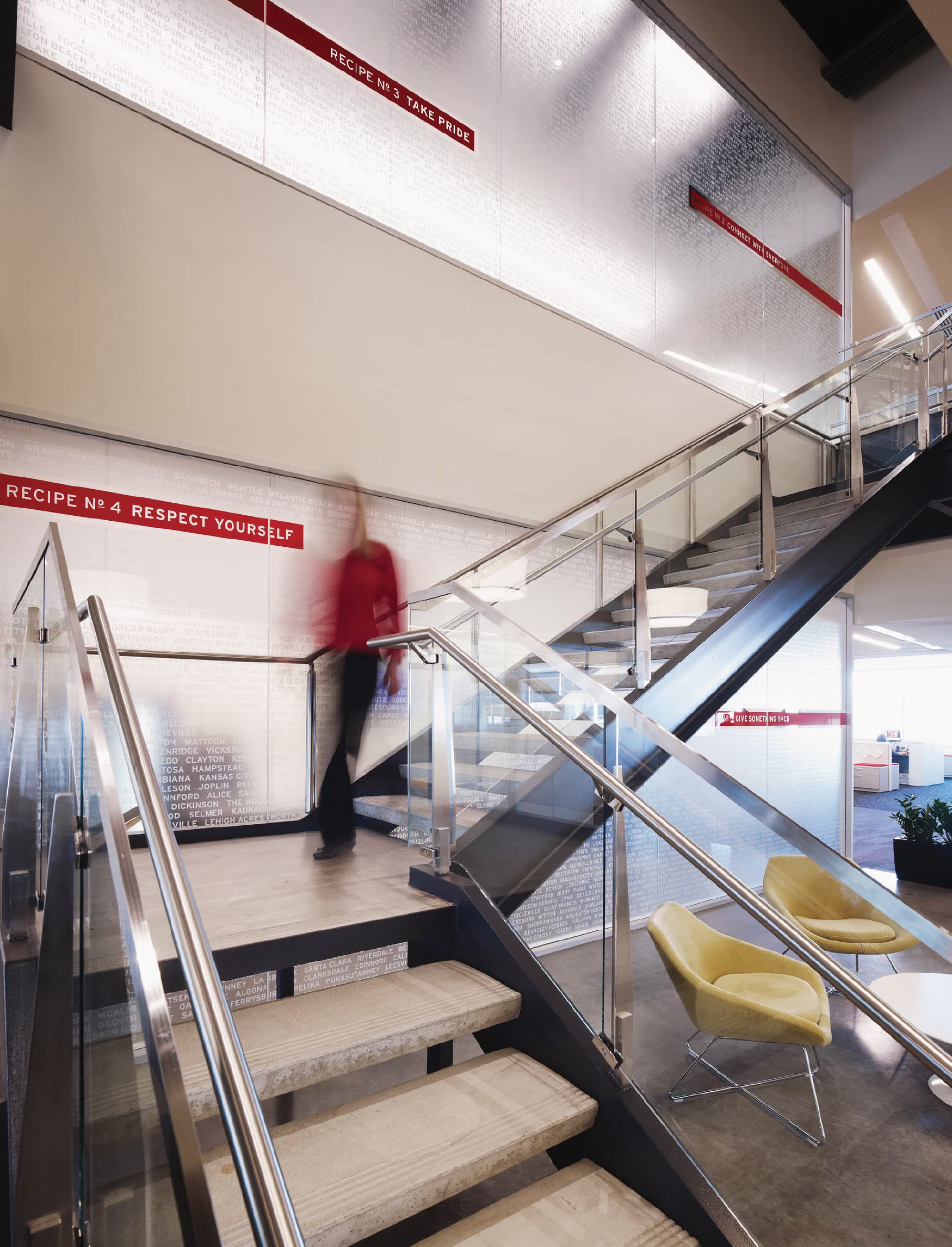 Interior workplace stair environment featuring large-scale environmental graphics and branded storytelling wall installations, illustrating experiential graphic design, brand communication, and placemaking within a corporate office and workplace environment.