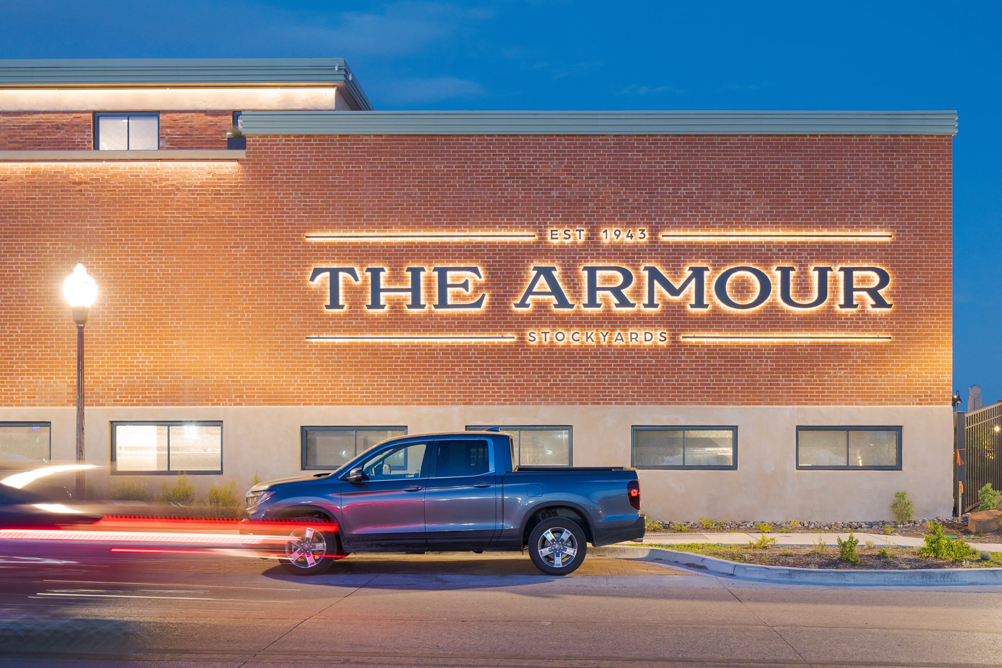 The Armour Stockyards illuminated brick facade signage at dusk, environmental graphic design by RSM Design