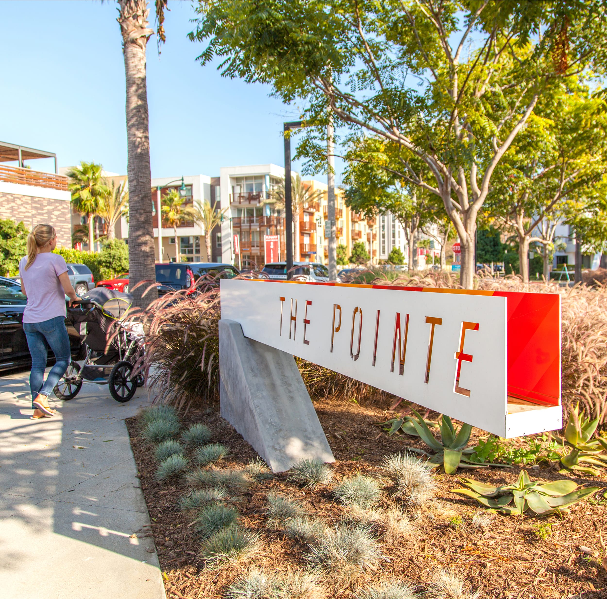Angled monument sign reading "THE POINTE," designed by RSM Design, with cut-out orange lettering set on a concrete base among landscaping in Playa Vista.