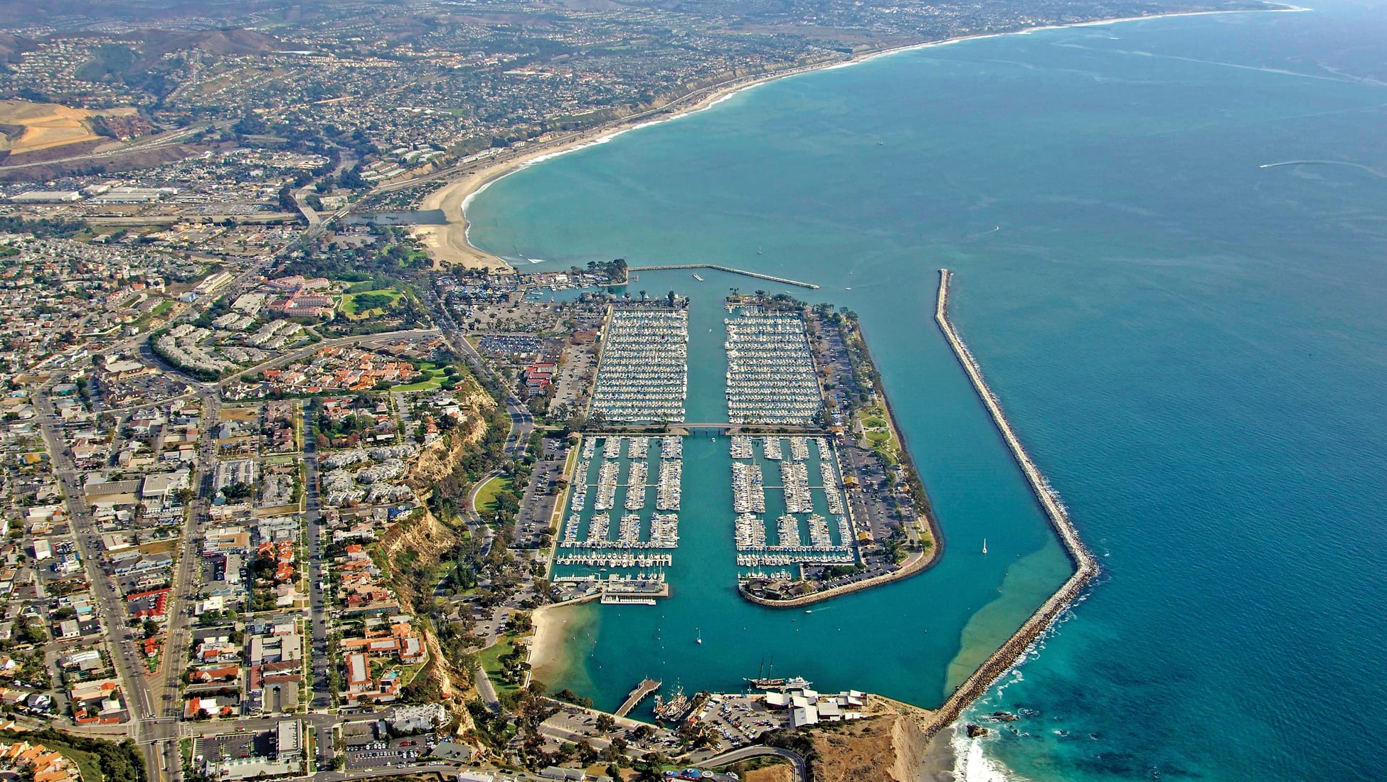 Aerial view of Dana Point Harbor's boat marinas, breakwater, and surrounding coastline