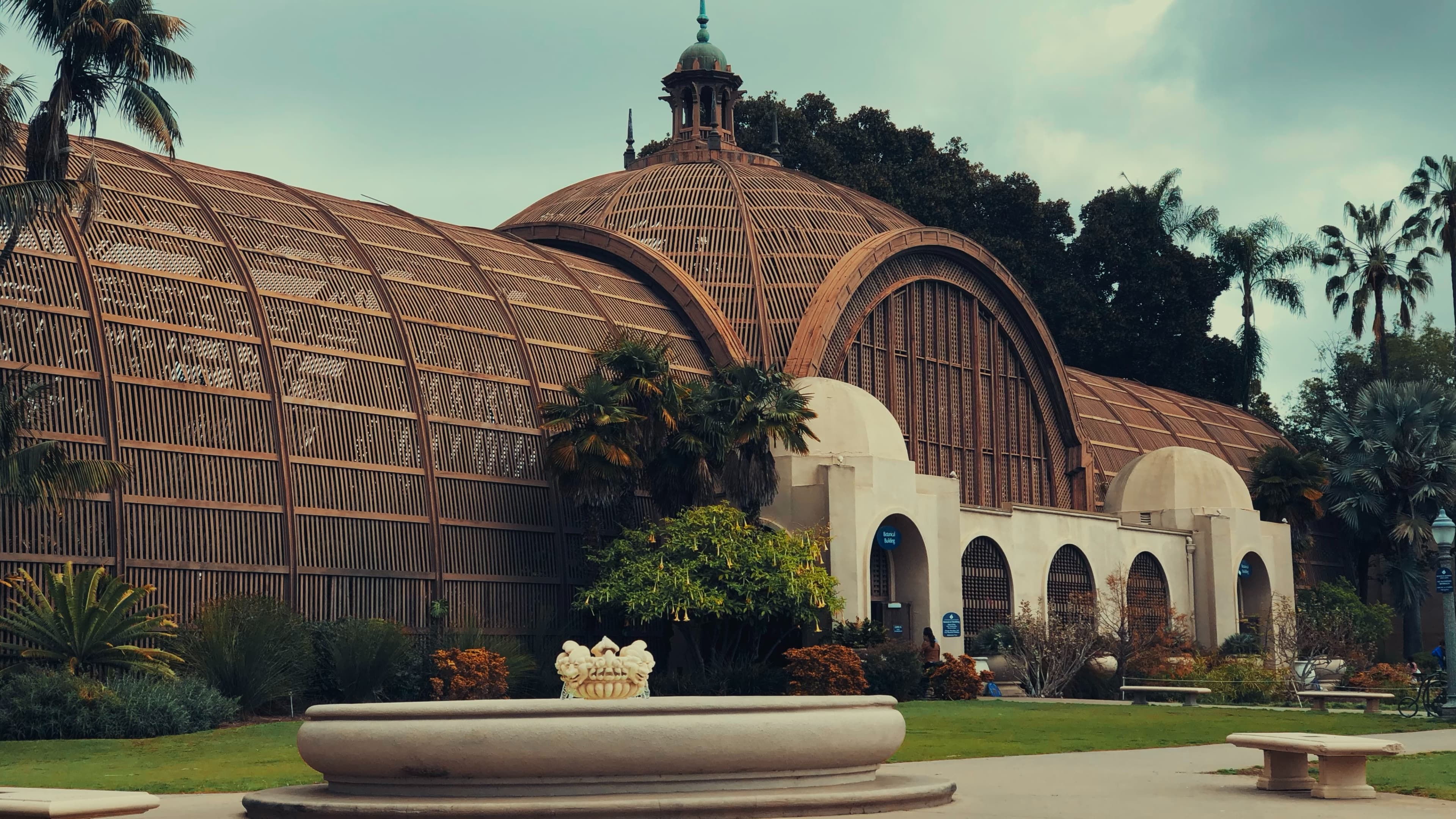 The iconic Balboa Park Botanical Building with blue sky and a fountain in the foreground