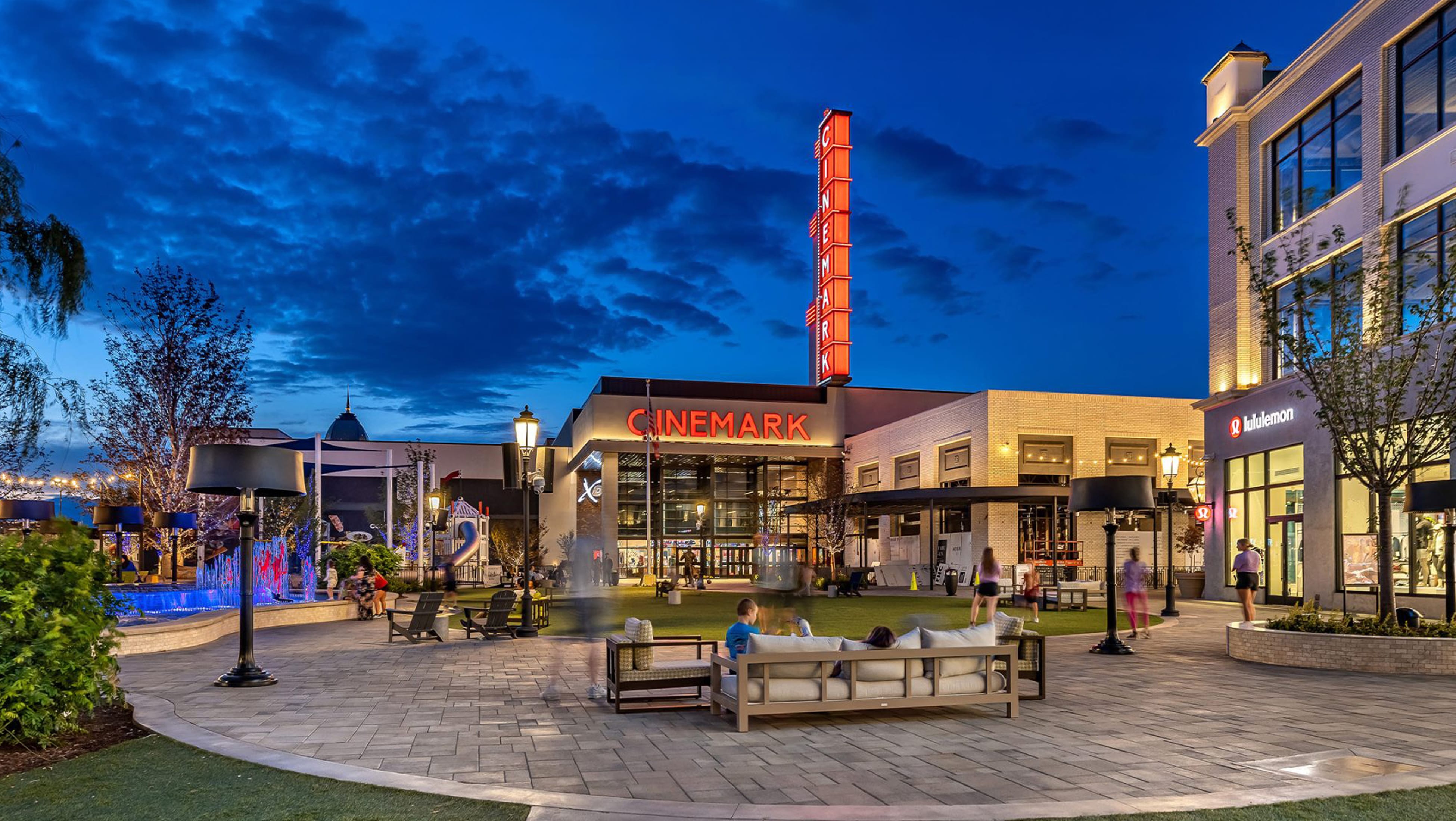 Cinemark theater marquee sign and outdoor lawn gathering space at Mountain View Village, a mixed-use retail center in Riverton, Utah — placemaking and environmental graphic design by RSM Design.