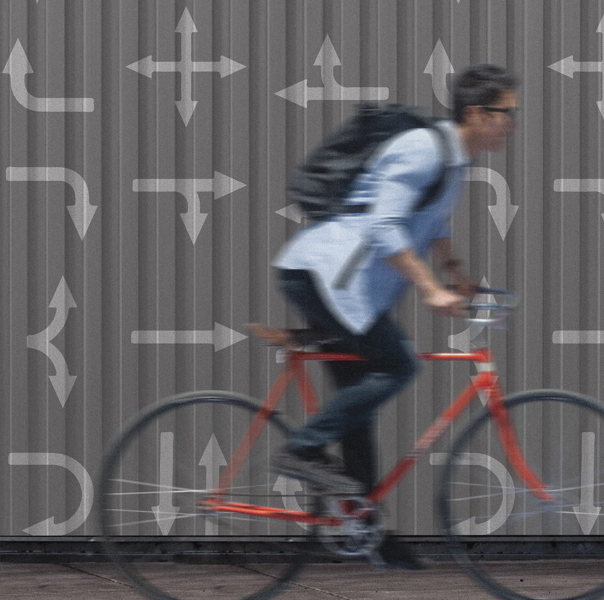 Cyclist riding past a graphic wall featuring directional arrow icons, illustrating environmental graphic design, wayfinding strategy, and placemaking that enhances movement and navigation within urban mixed-use environments.