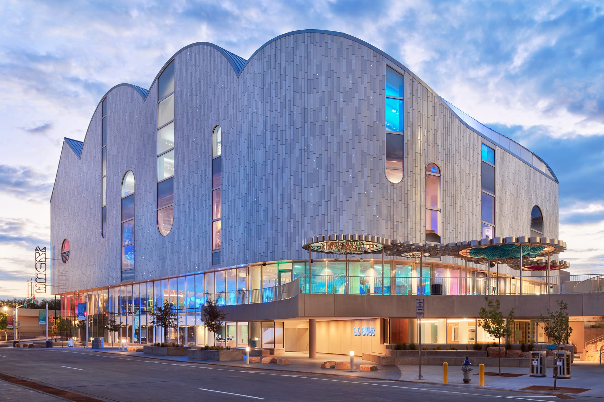 La Nube children's museum full exterior at dusk with illuminated cloud-form facade, neon signage, and colorful interior visible through ground-floor glazing — …La Nube children's museum full exterior at dusk with illuminated cloud-form facade, neon signage, and colorful interior visible through ground-floor glazing — environmental graphic design by RSM Design