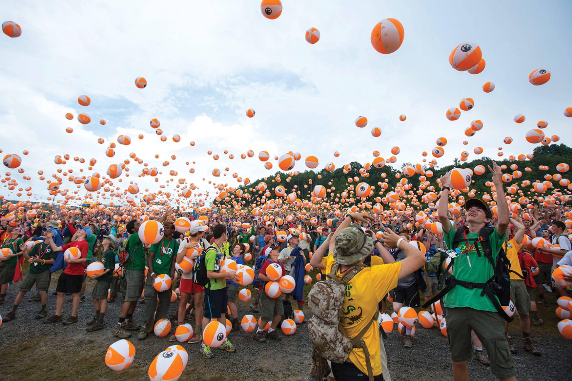 Thousands of scouts tossing branded orange and white beach balls at National Scout Jamboree opening ceremony at Summit Bechtel Reserve, large-scale event branding and experiential design by RSM Design