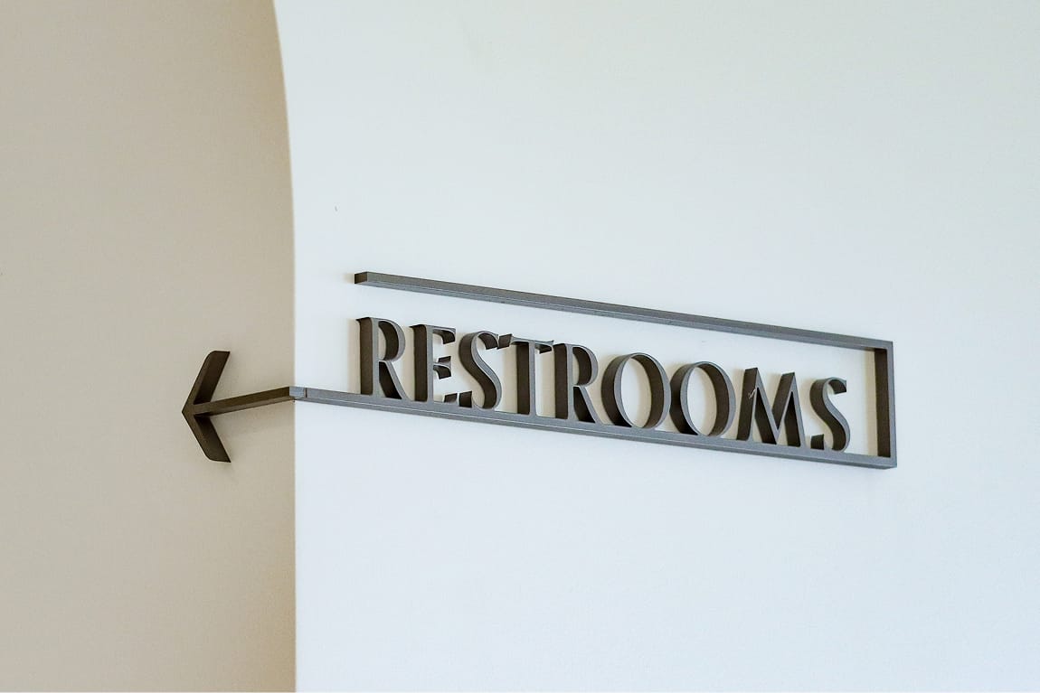 Framed directional sign reading "Restrooms" with an arrow on an archway wall at Maple Terrace - environmental graphic design by RSM Design