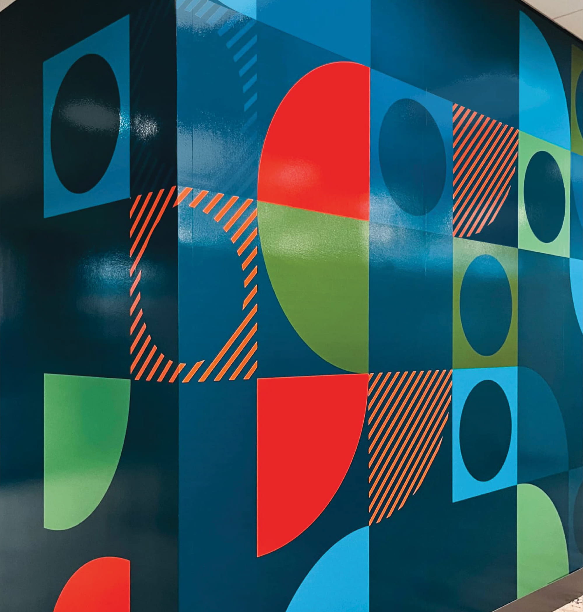 Bold geometric wall graphics in a workplace interior, showcasing environmental graphic design, brand strategy, and experiential design that activate the space through color, pattern, and placemaking for corporate and innovation-focused environments.