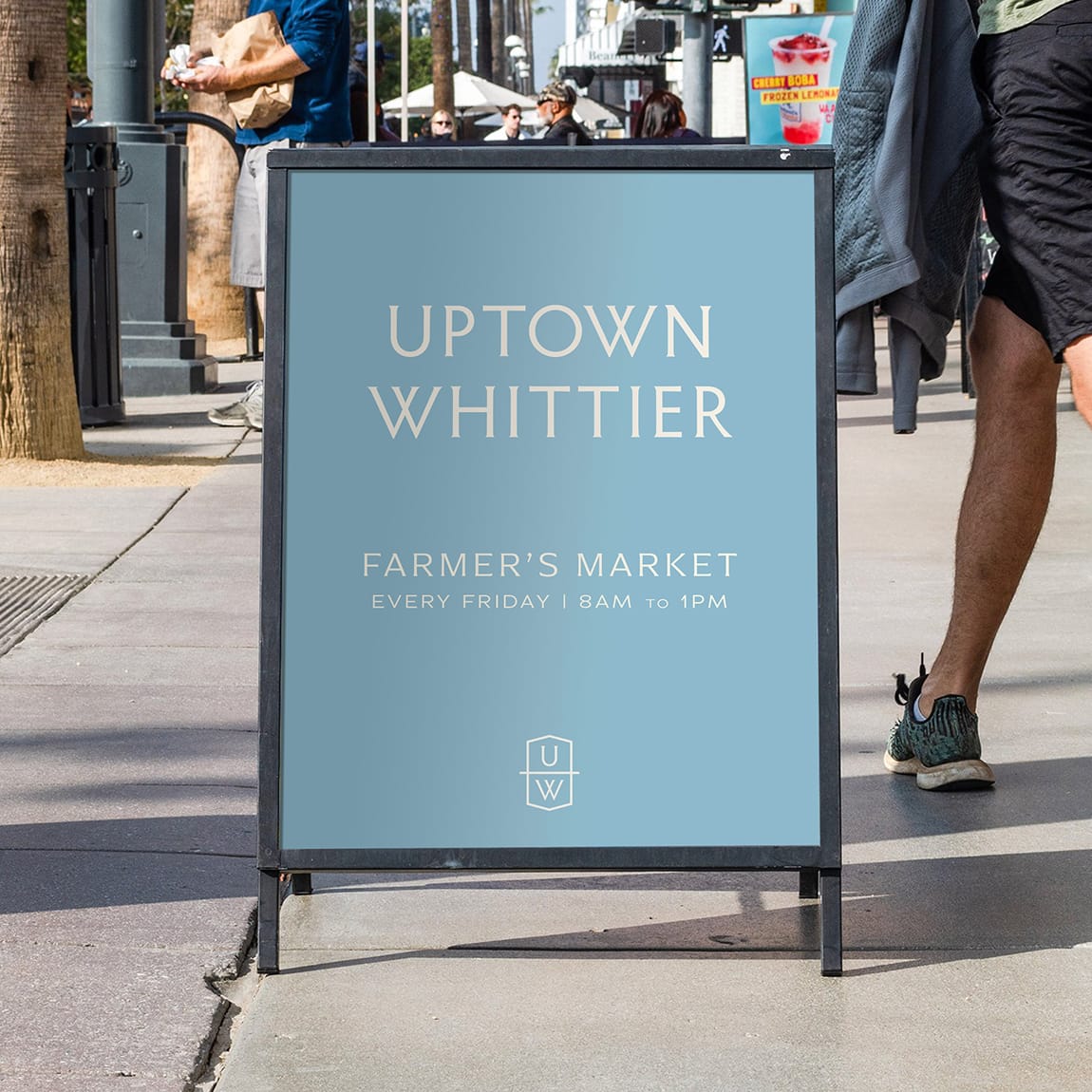 Uptown Whittier sidewalk signage promoting the farmer’s market, featuring clean typography and a soft color palette that integrates seamlessly into the streetscape.