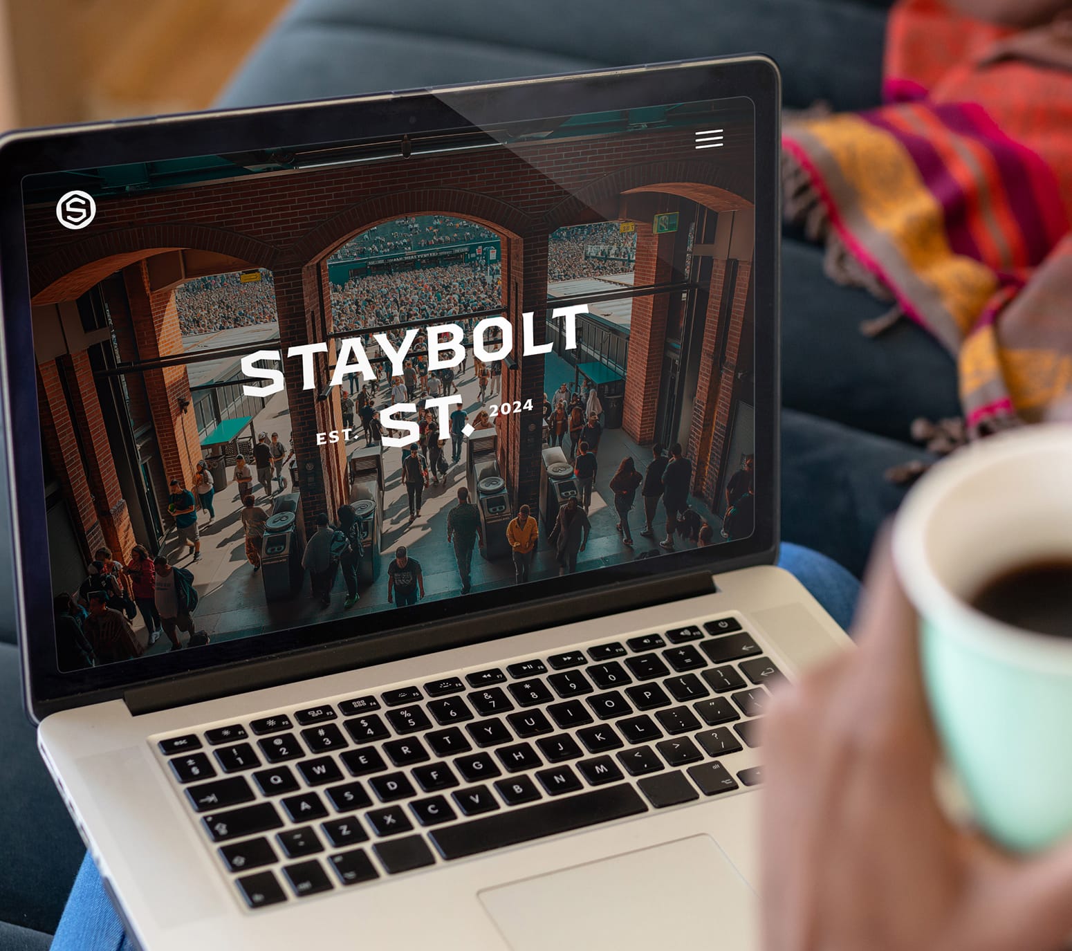 Staybolt Street website homepage displayed on laptop with district identity and stadium crowd imagery — branding by RSM Design