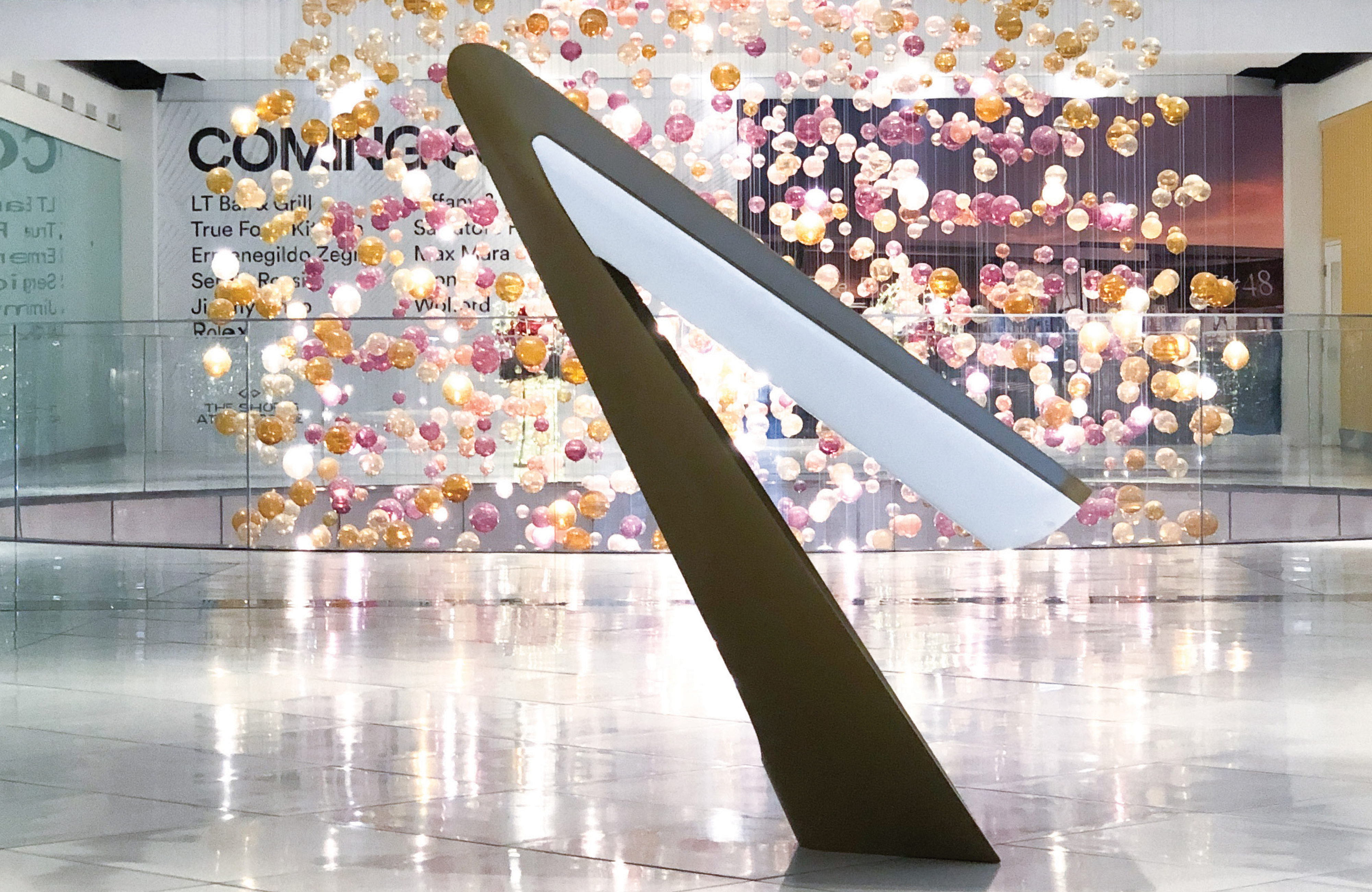 Interactive digital directory kiosk within a retail mall featuring a large-scale art installation, illustrating environmental graphic design, wayfinding systems, and placemaking that enhance navigation and visitor experience in mixed-use retail destinations.
