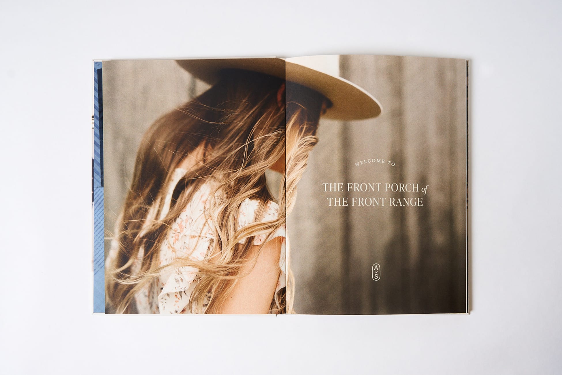 Open brand book spread with windswept model in wide-brim hat facing "Welcome to the Front Porch of the Front Range" headline and monogram, brand identity book design by RSM Design.