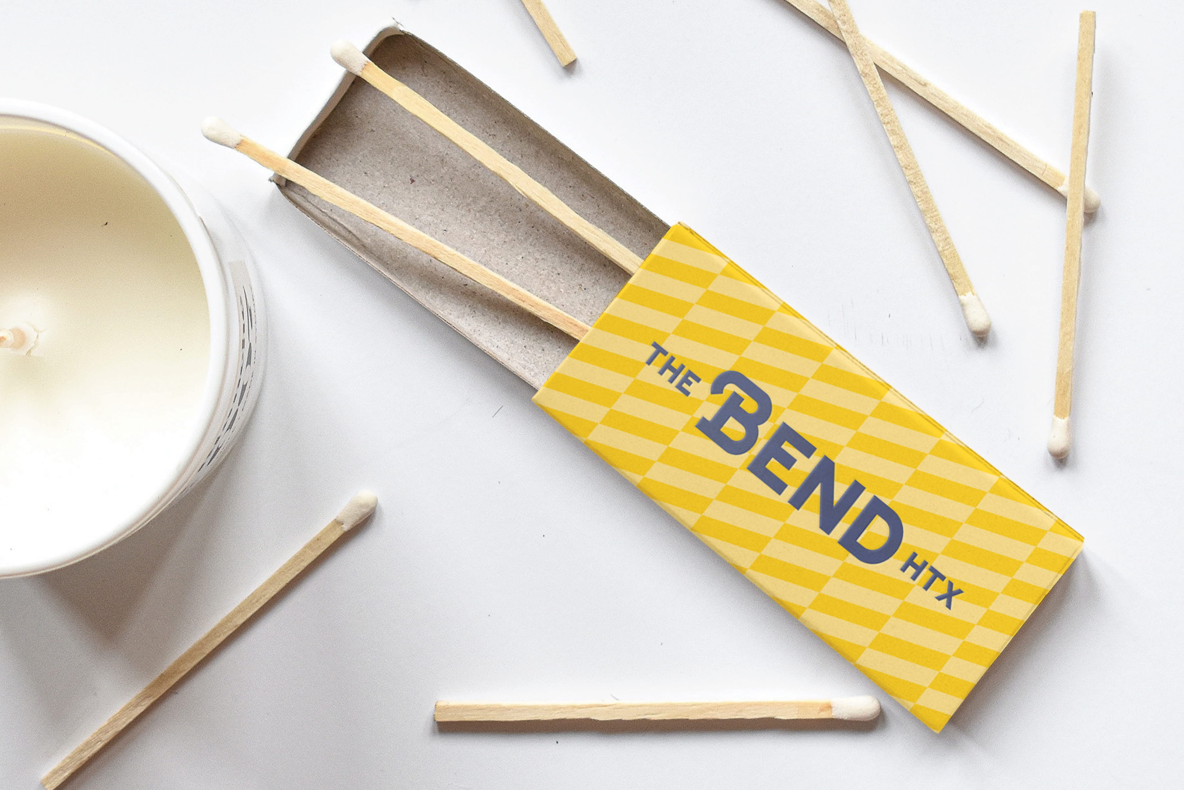 Branded matchbox for The Bend HTX placed beside a candle and matches, highlighting brand identity design, graphic design, and experiential branding that support placemaking within a mixed-use retail, dining, and entertainment destination.