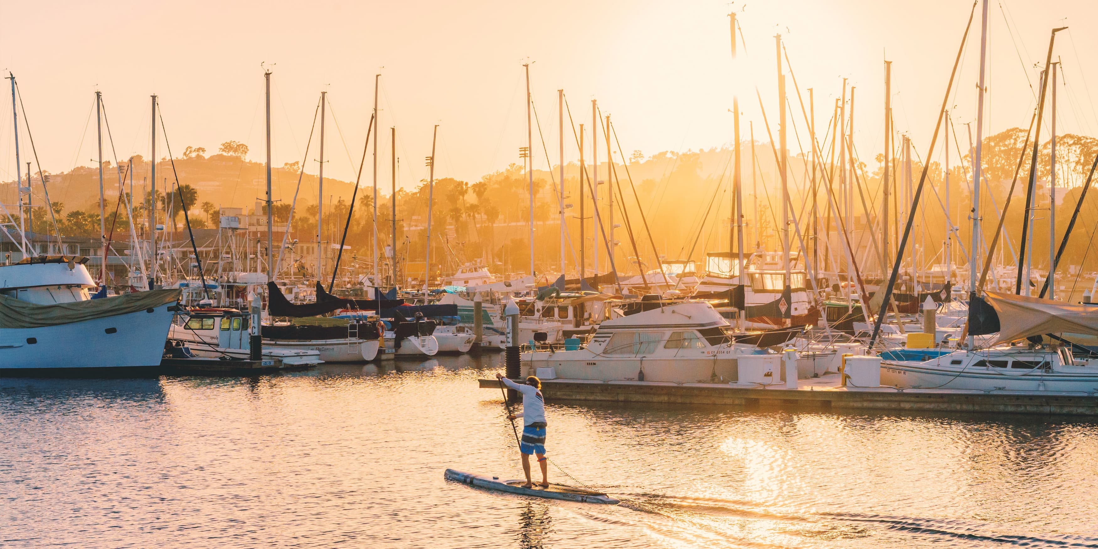 The City of Dana Point, man paddle-boards at sunset in the Dana Point Harbor