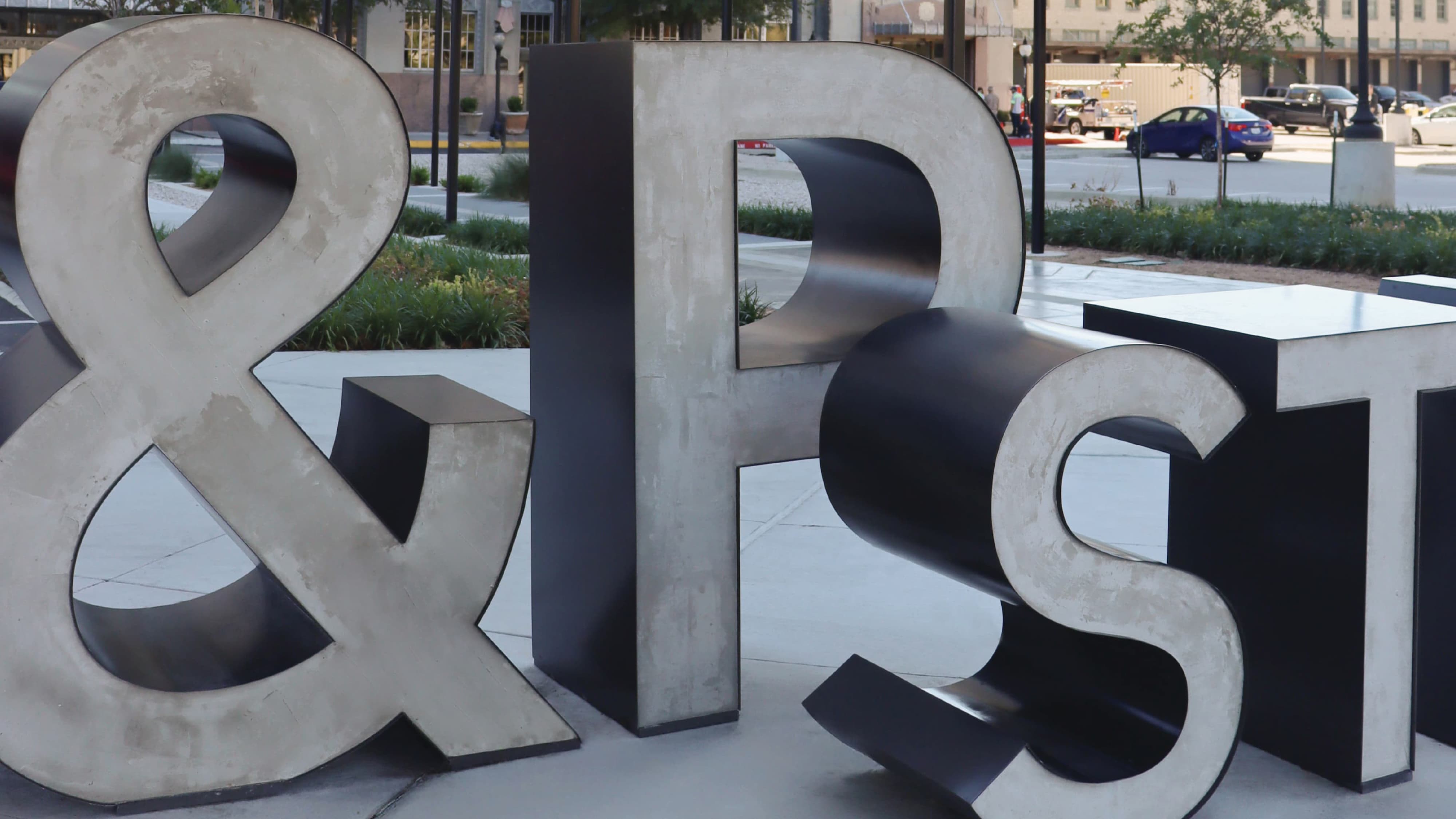 Close-up of large-scale concrete and black steel dimensional "T&P Station" letters in an outdoor plaza, showcasing experiential graphics and placemaking design for a mixed-use transit and streetscape development by RSM Design.