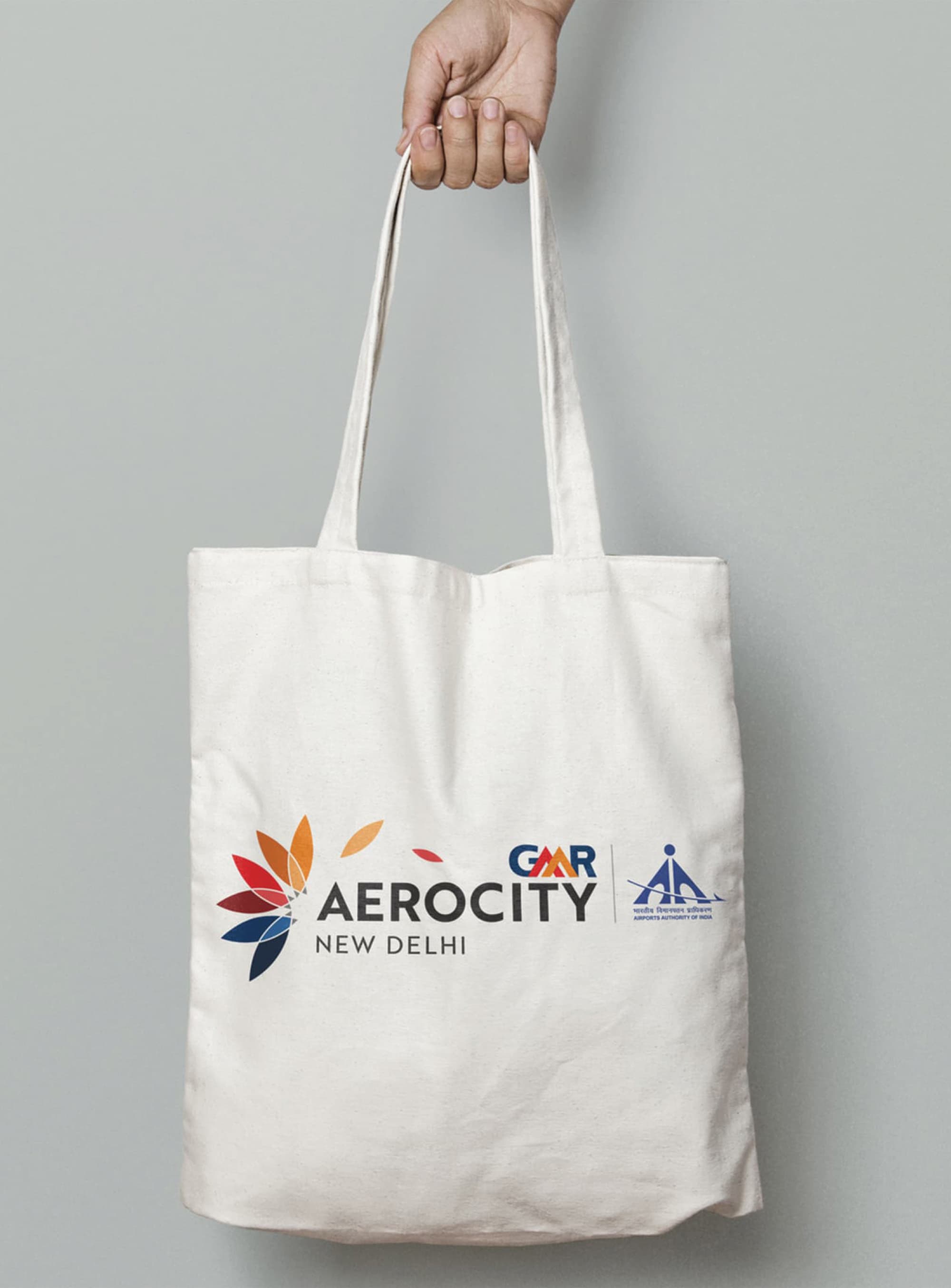 GMR Aerocity New Delhi branded canvas tote bag with multicolored lotus flower logo and Airports Authority of India co-branding — RSM Design branding and visual identity, print and digital collateral, and specialty graphics for mixed-use, transit, and international destinations.