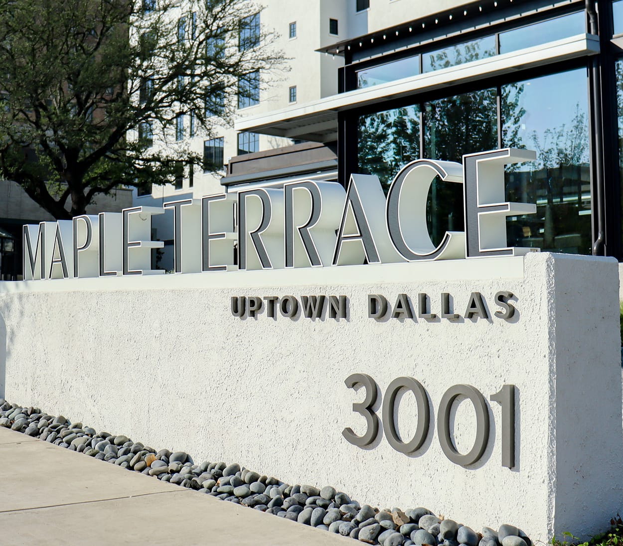 Close-up of dimensional letters reading "Maple Terrace, Uptown Dallas, 3001" on a stucco monument sign - environmental graphic design by RSM Design