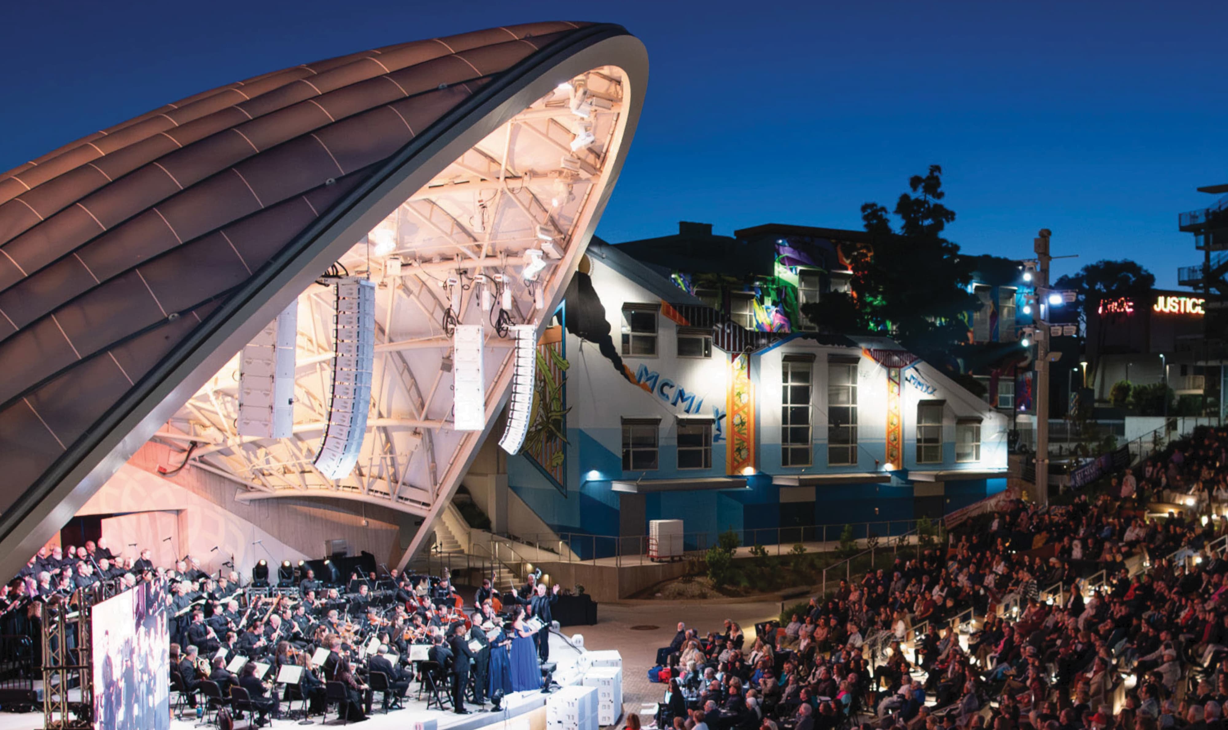 Outdoor amphitheater performance at night within a mixed-use entertainment district, showcasing experiential design, environmental graphics, and wayfinding that support arts, culture, and public space placemaking by RSM Design