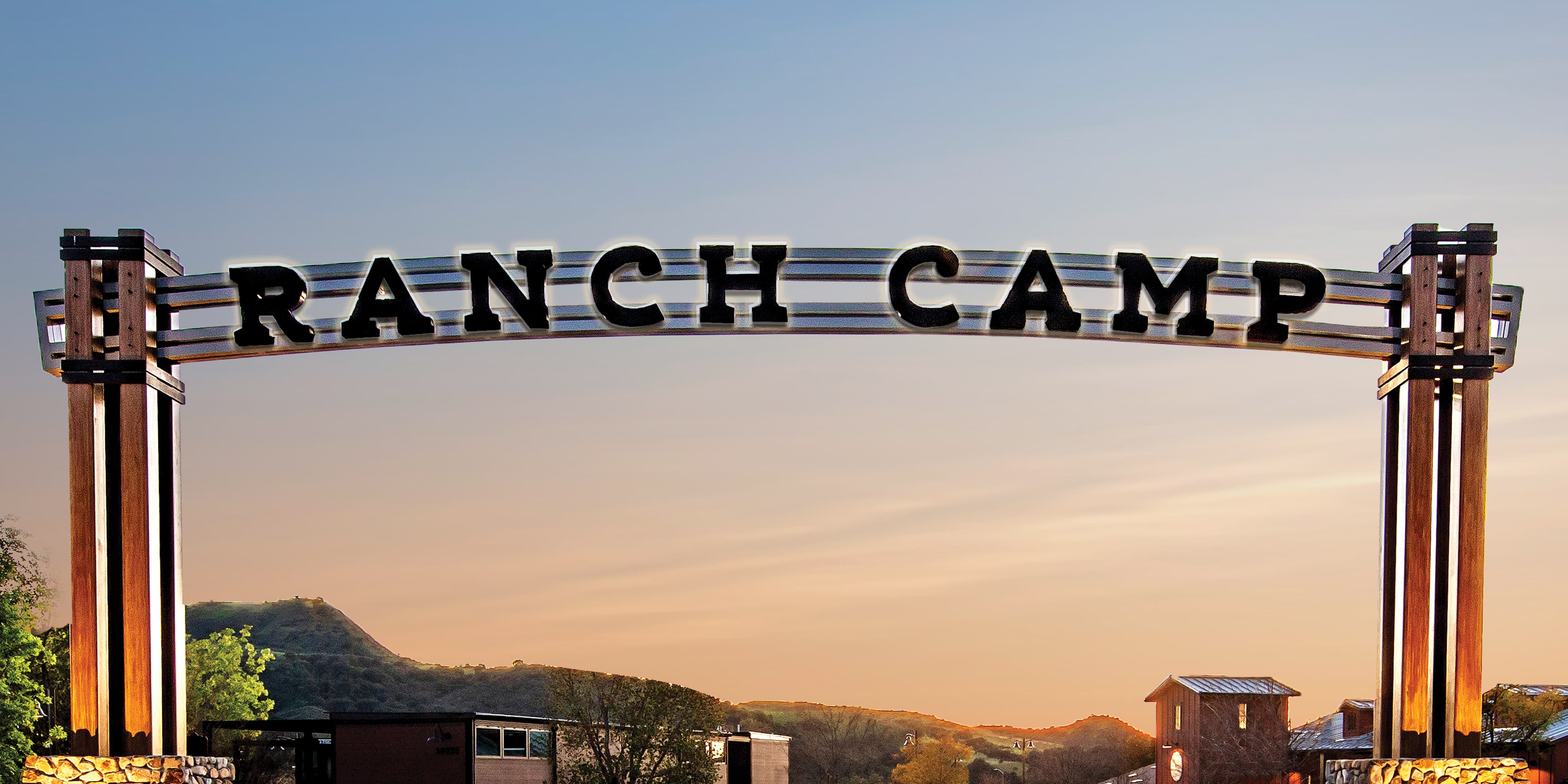 Illuminated Ranch Camp overhead sign for entry point of Ranch Camp, in Rancho Mission Viejo. Glowing sign at sunset done in large lettering by RSM Design.  