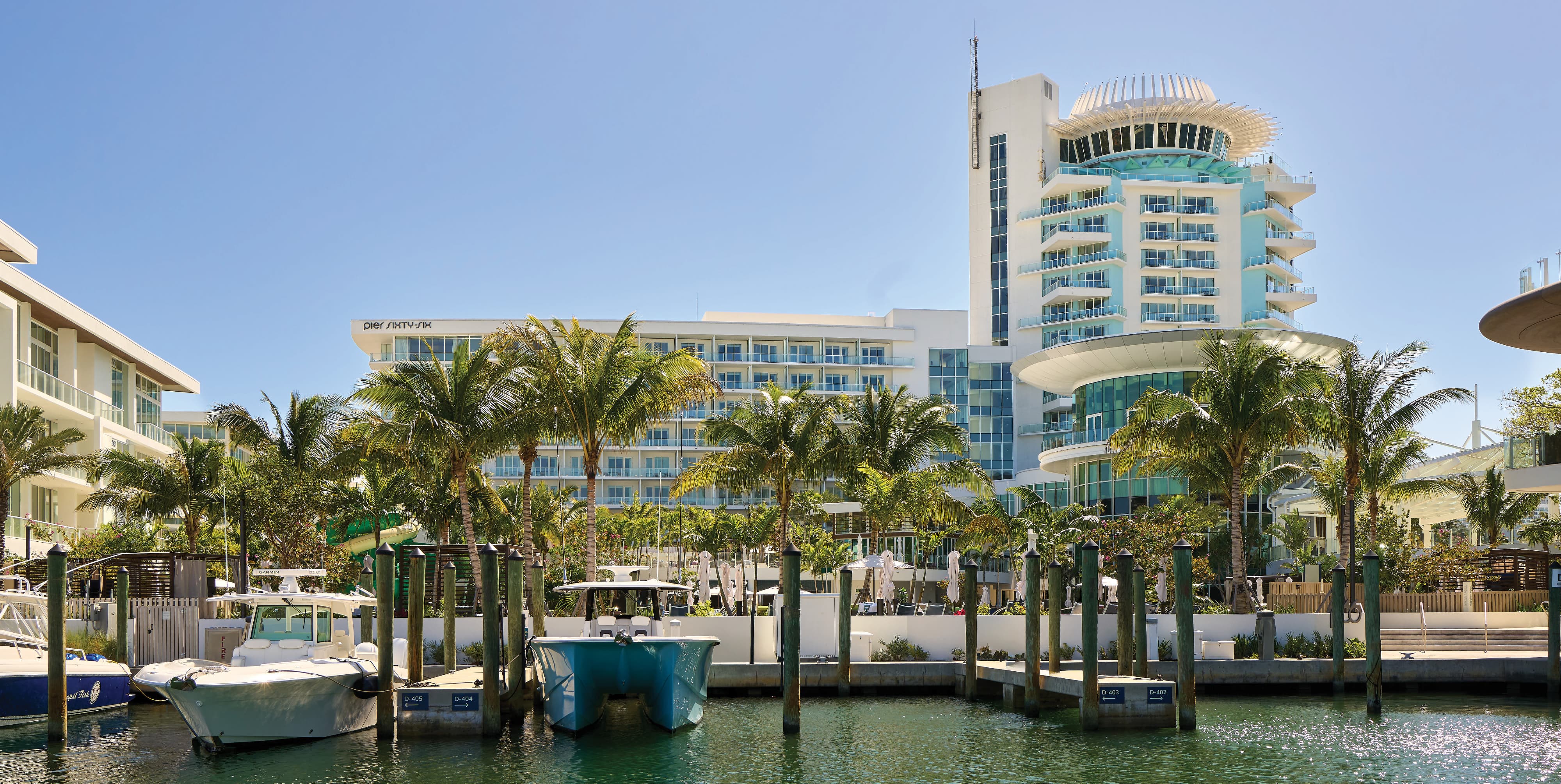 Marina waterfront view of Pier Sixty-Six luxury resort in Fort Lauderdale, Florida, featuring exterior building identification signage, branded marina dock slip identification signs, iconic rotating tower, and poolside placemaking amid tropical palm trees — RSM Design wayfinding and signage design, master sign programs, environmental graphic design, and experiential placemaking for hospitality, waterfront, and residential community destinations.