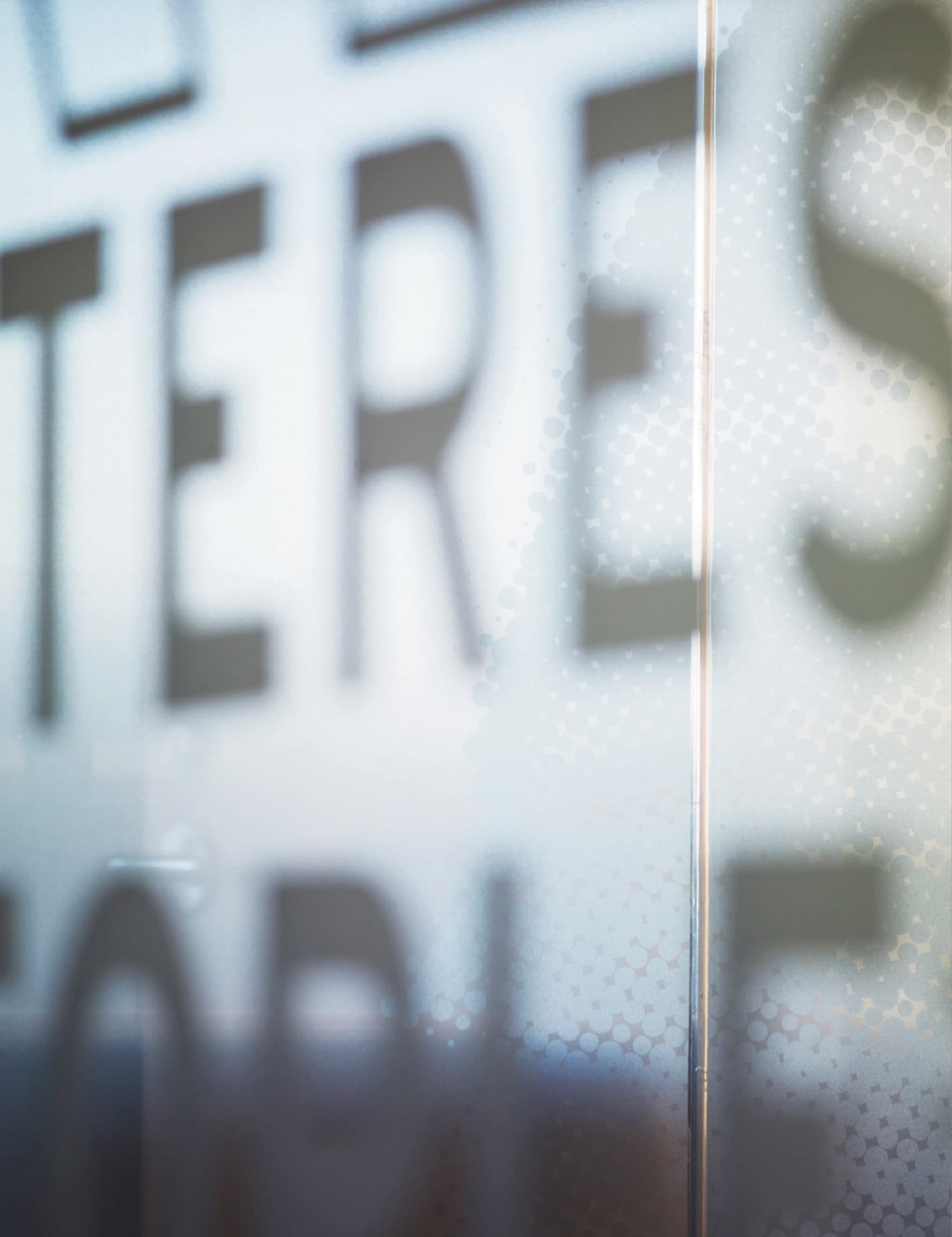 Close-up detail of glass wall environmental graphics and typography within a corporate workplace interior, illustrating experiential graphic design, branded environments, and placemaking in a modern office setting.