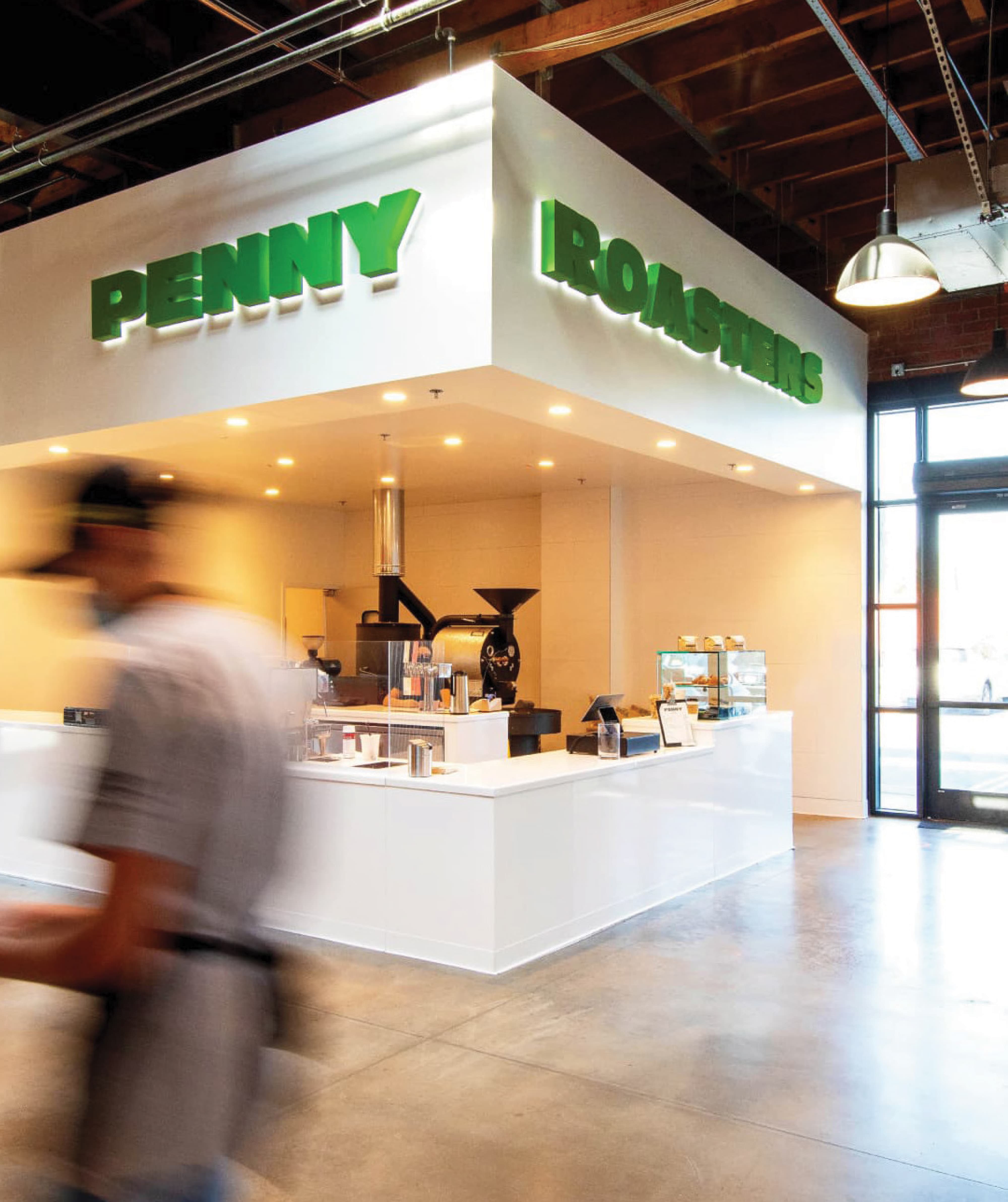 Penny Roasters coffee bar within a public market, featuring branded environmental graphics, identity signage, and wayfinding design that enhance the retail and hospitality experience in a mixed-use destination by RSM Design