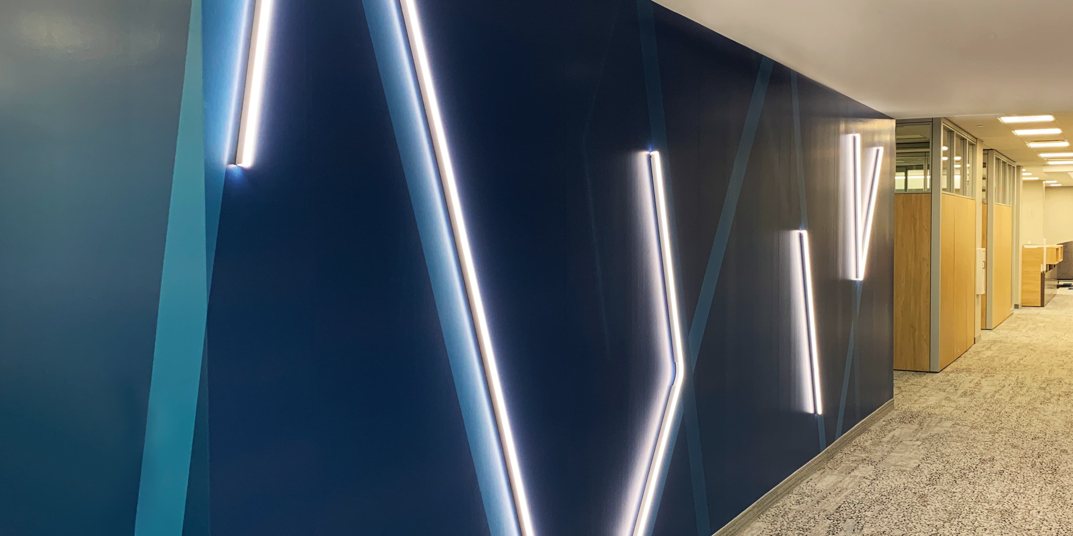 Speciality art mural by RSM Design for JMFE Headquarters consisting of blue bent neon signage for office workplace design.k