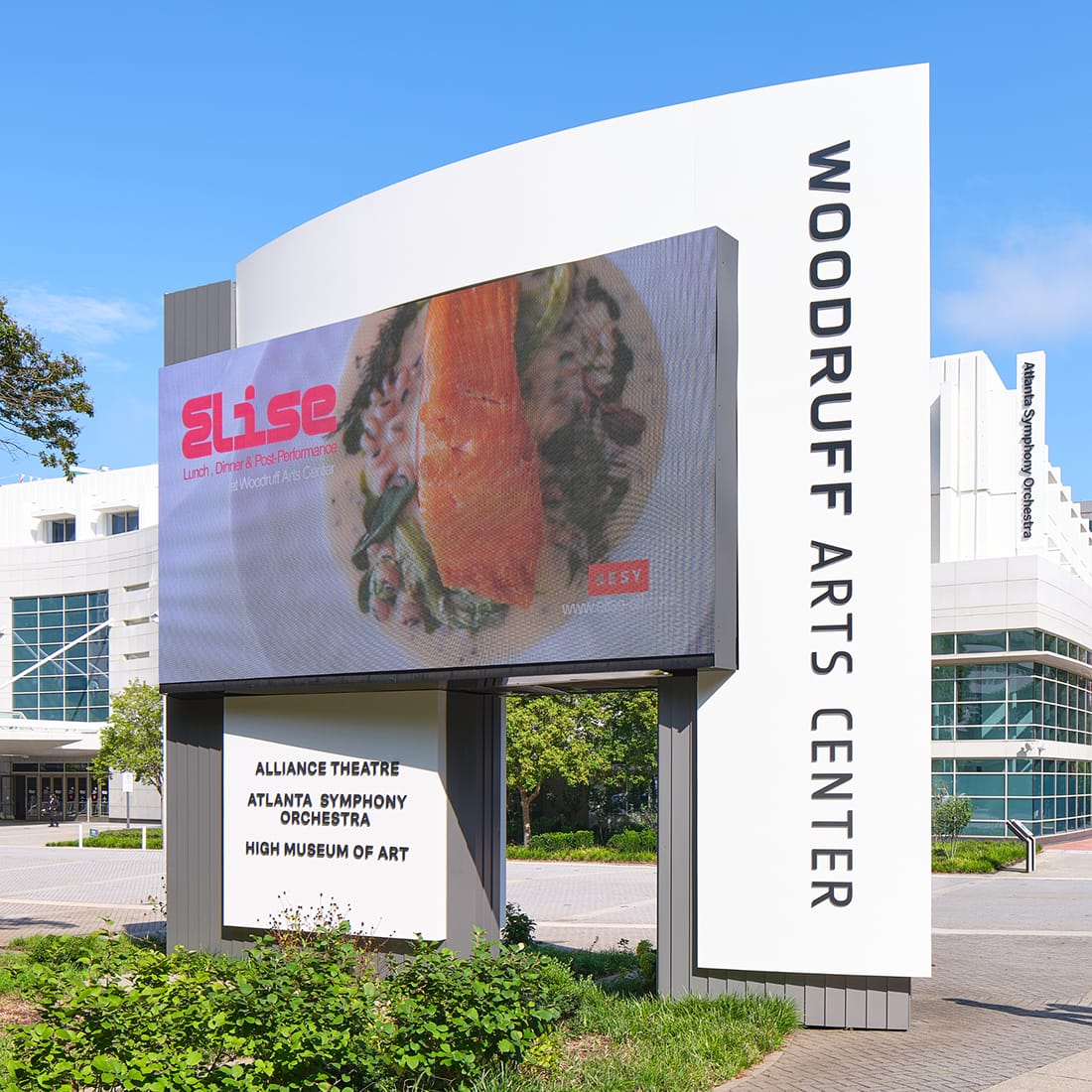 Curved pylon sign with digital display and vertical "WOODRUFF ARTS CENTER" lettering listing the Alliance Theatre, Atlanta Symphony Orchestra, and High Museum of Art – campus wayfinding and environmental graphic design by RSM Design.