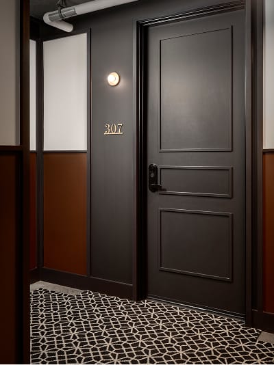 Residential corridor at Fifth + Broadway featuring unit number signage and refined material detailing that reinforces a cohesive interior identity.