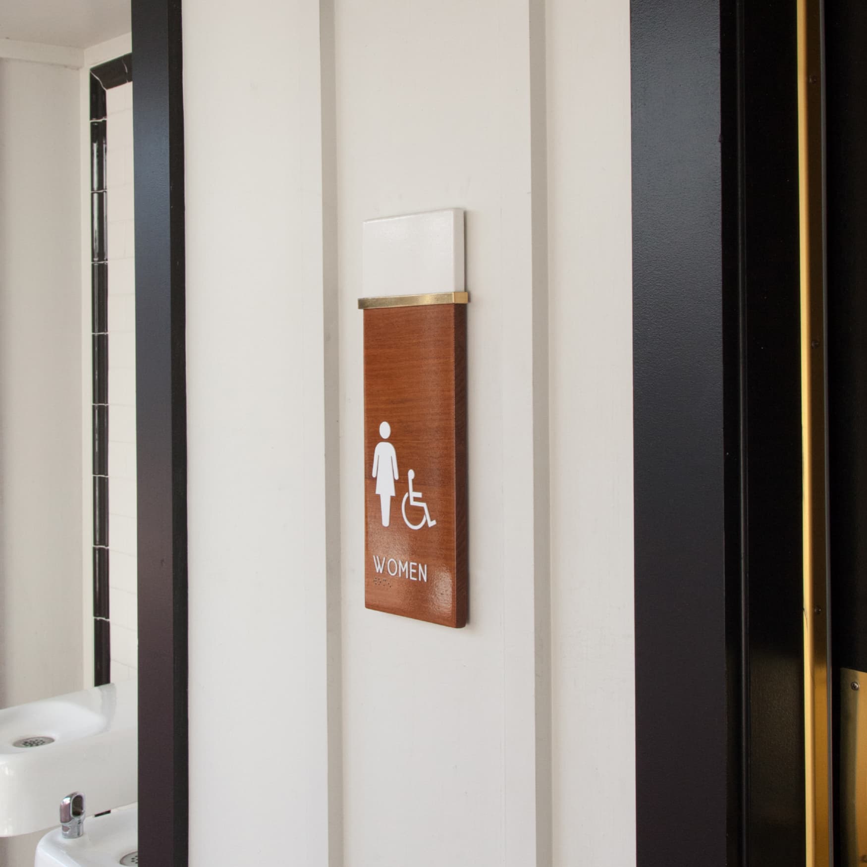 Image of the women's restroom identity sign. Wooden signage with gloss coating. 