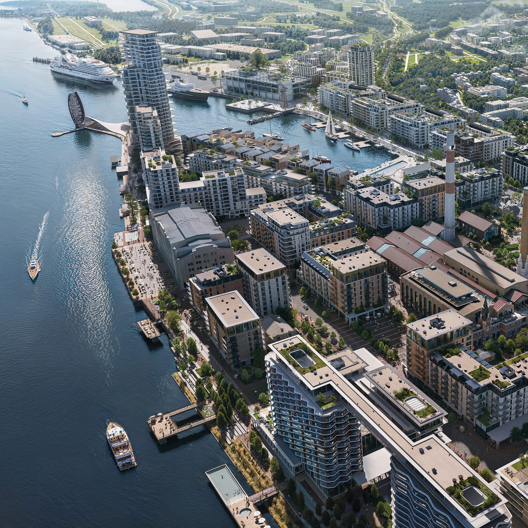 Aerial view of a waterfront mixed-use district featuring modern residential buildings, landscaped public spaces, marina boats, and historic industrial architecture along the river.