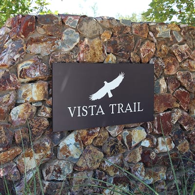 Close-up of the "Vista Trail" sign with a bird icon set into a stone wall at Terramor - environmental graphic design by RSM Design