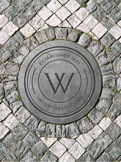 City of Whittier branded pavement medallion featuring the “W” mark with “Established 1887” and “Incorporated 1898,” integrated into textured stonework to reinforce identity within the built environment.