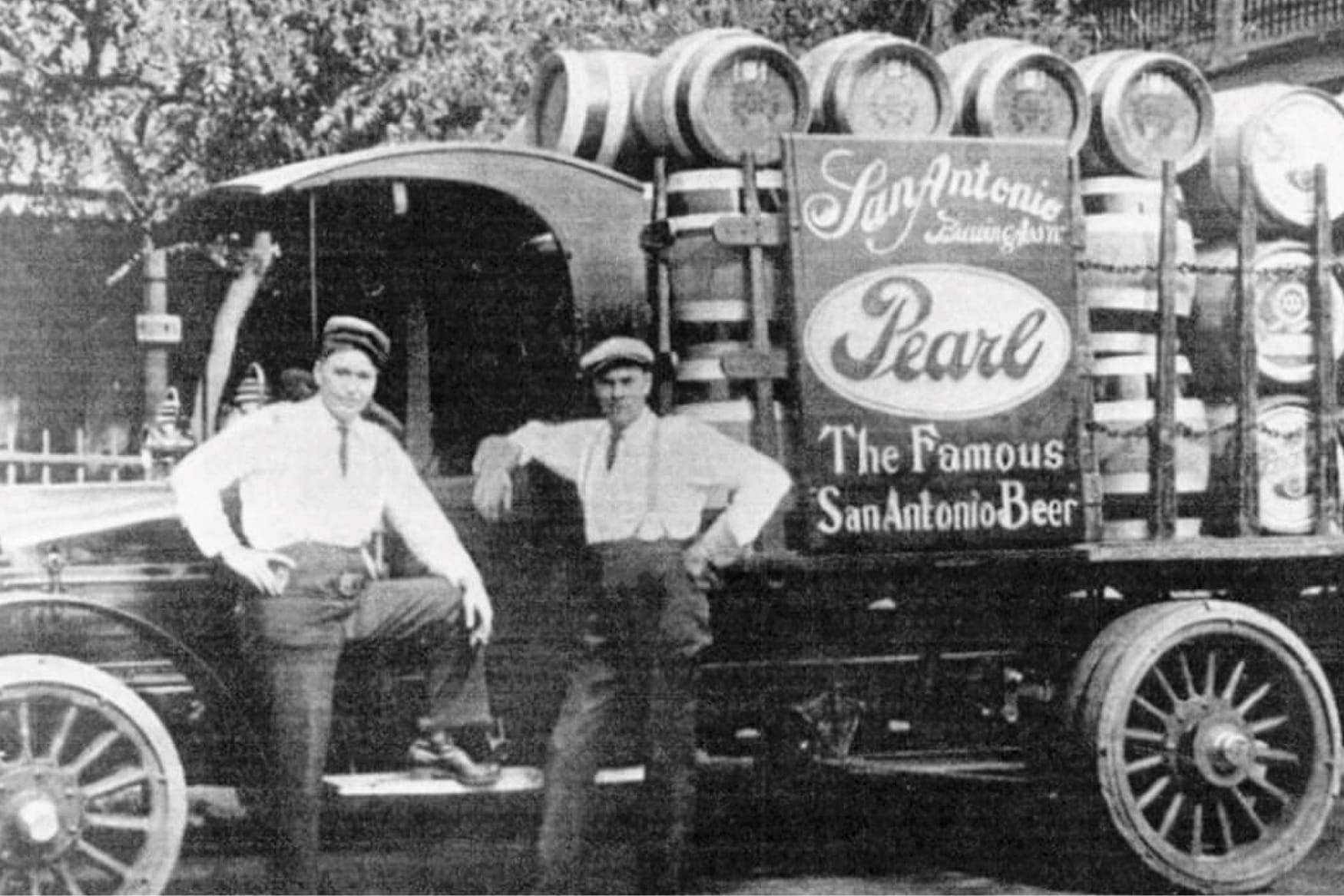 Historic black-and-white photo of a vintage Pearl beer delivery truck in San Antonio, featuring wooden barrels, painted Pearl signage, and brewery workers, reflecting the heritage of the Pearl Brewery district.