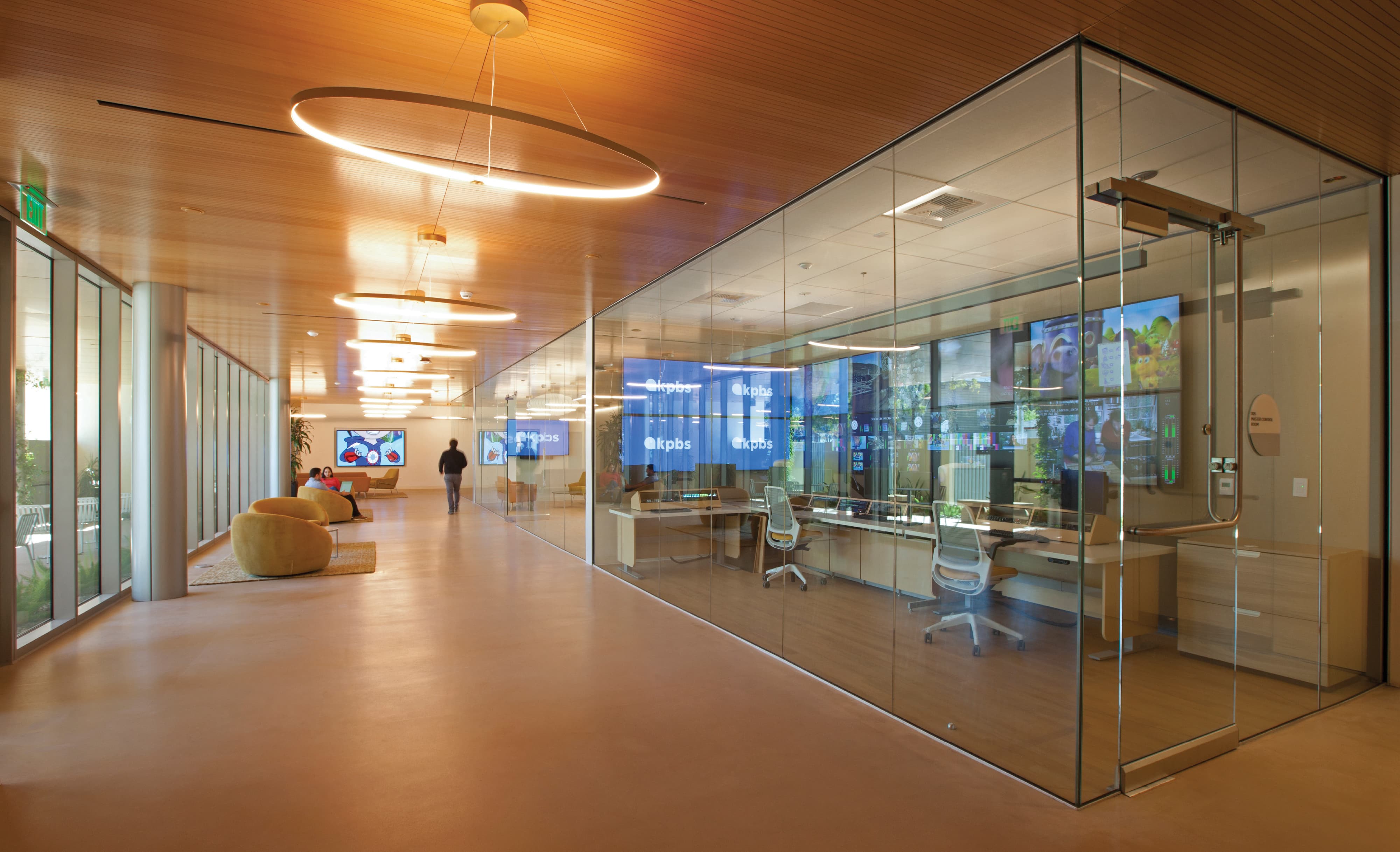 Contemporary media workplace interior with glass-enclosed control room, integrated digital displays, and branded environmental graphics, showcasing RSM Design expertise in experiential design, wayfinding, and identity for media, corporate, and institutional environments.