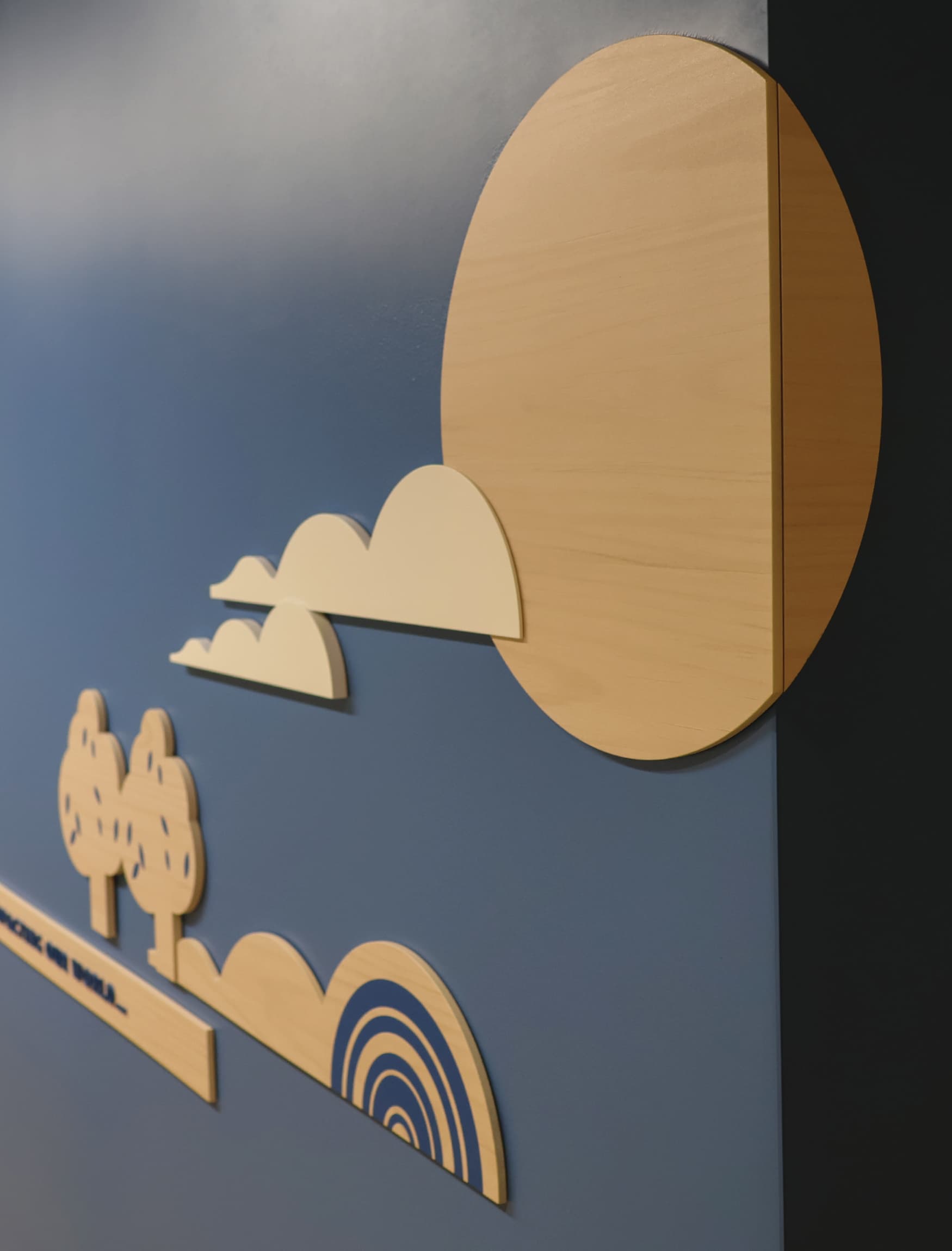 The wall in the image is part of the permanent exhibition designed by RSM Design for the UCLA Fielding School of Public Health's 60th anniversary. It features a vibrant and informative display with a variety of graphic elements and icons. Key public health themes such as Inclusion, Equity, Evidence, Prevention, Community, and Impact are highlighted on the wall, each with its own distinct section. The design includes detailed illustrations, representing different aspects of public health and the school's contributions to the field. The wall is well-lit and incorporates wooden textures with colorful visual elements, making the information engaging and accessible. There are also seating benches integrated into the design, inviting viewers to spend time interacting with the exhibit.