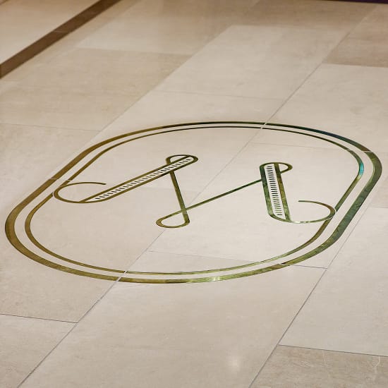 Brass "MT" monogram inlaid in the stone lobby floor at Maple Terrace - environmental graphic design by RSM Design