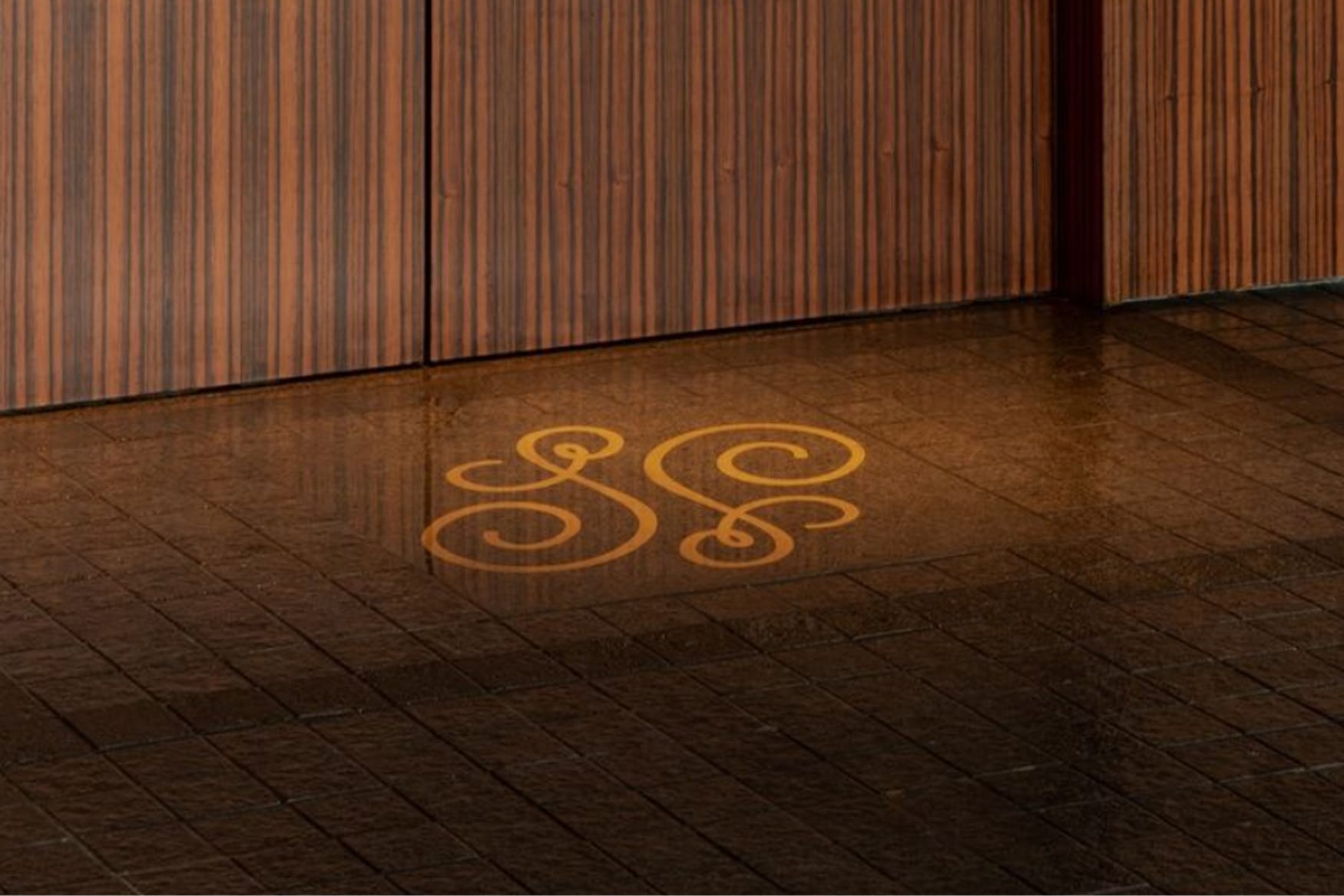 Ornate gold "SS" monogram projected onto the entrance floor at The Swexan Hotel - environmental graphic design by RSM Design