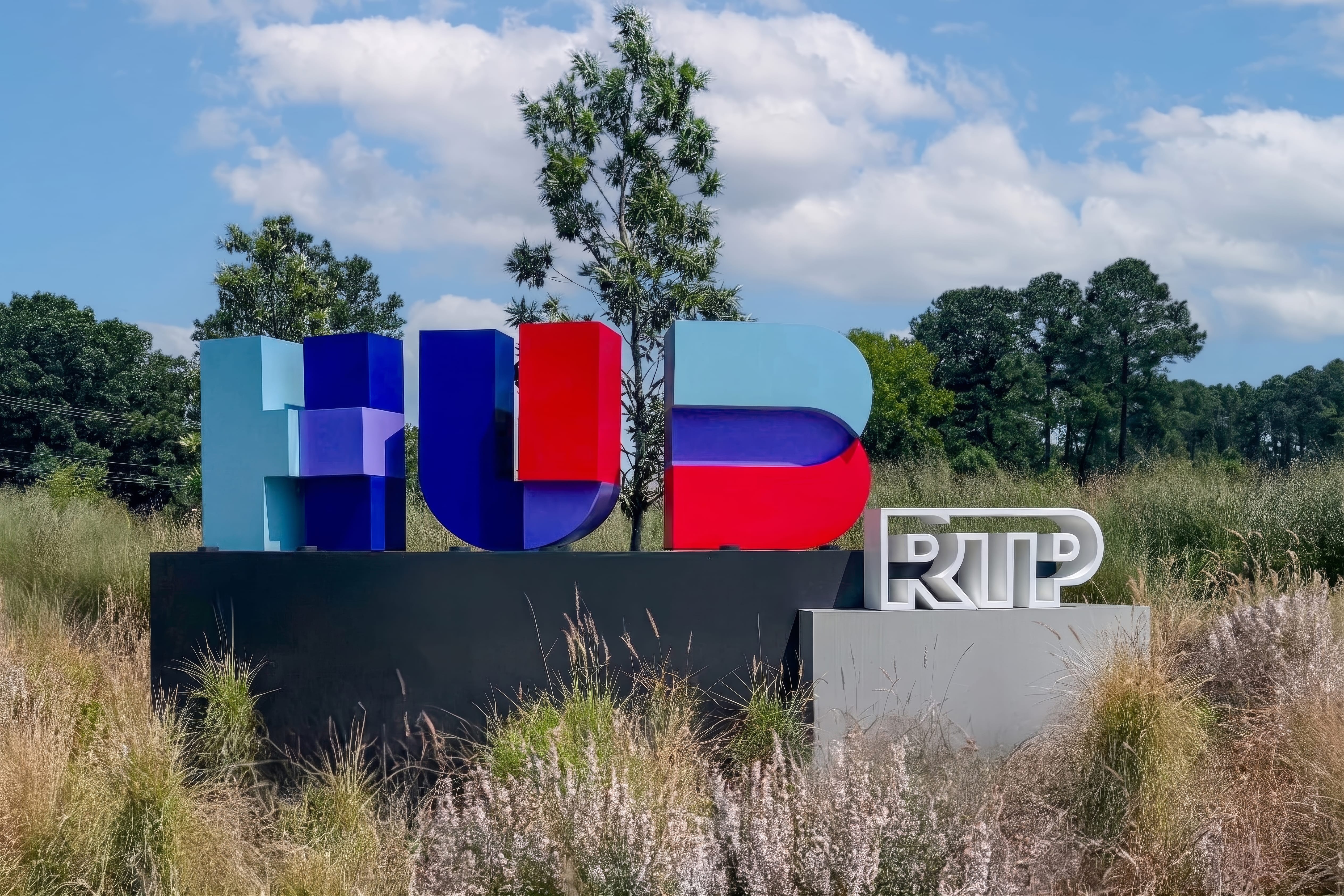 RSM Design branded monument sign for HUB RTP — bold colorful dimensional letter signage surrounded by native grasses and trees at Research Triangle Park, Durham NC