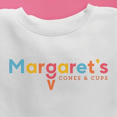 Margaret's Cones and Cups branded white crewneck sweatshirt featuring colorful multi-colored retro logo, ice cream shop merchandise design at Omni PGA Frisco