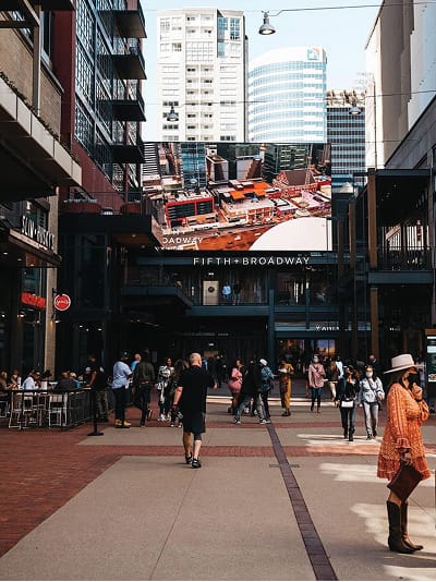 A central gathering corridor frames layered views of the district, where integrated signage and digital media create a cohesive, active environment that encourages exploration and connection.