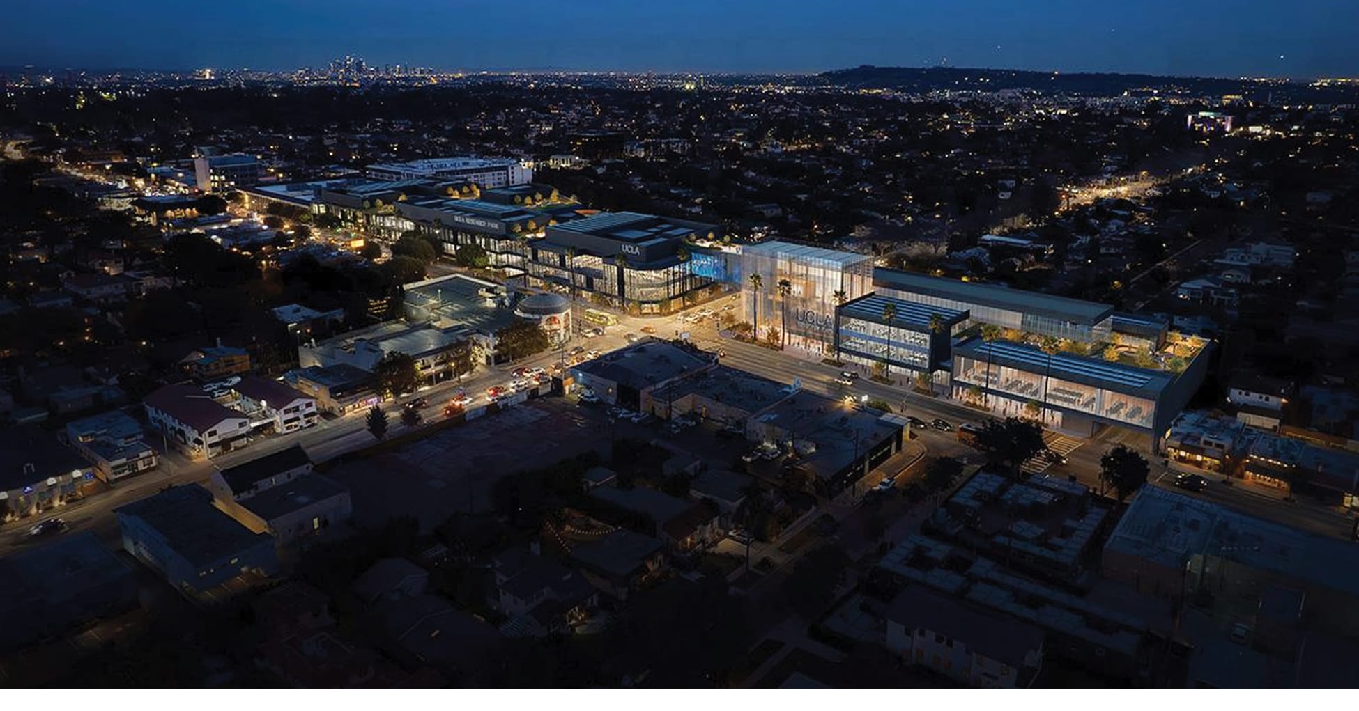 Aerial view of UCLA Research Park in Los Angeles at night, showcasing illuminated campus buildings, integrated signage, and urban connectivity within a contemporary research and innovation district designed by RSM Design.