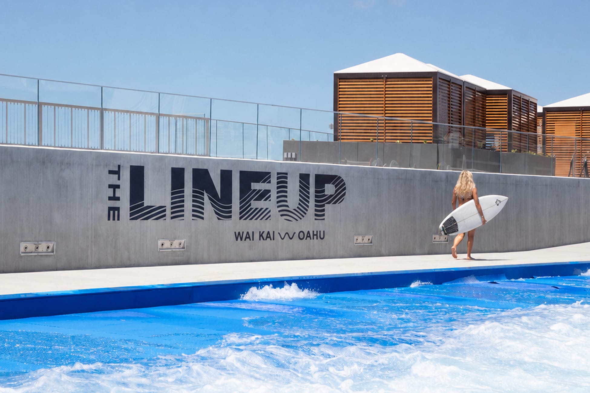 Surfer walking beside "The Lineup" wall graphic overlooking wave pool at Wai Kai, Ewa Beach, Oahu, environmental graphic design by RSM Design.
