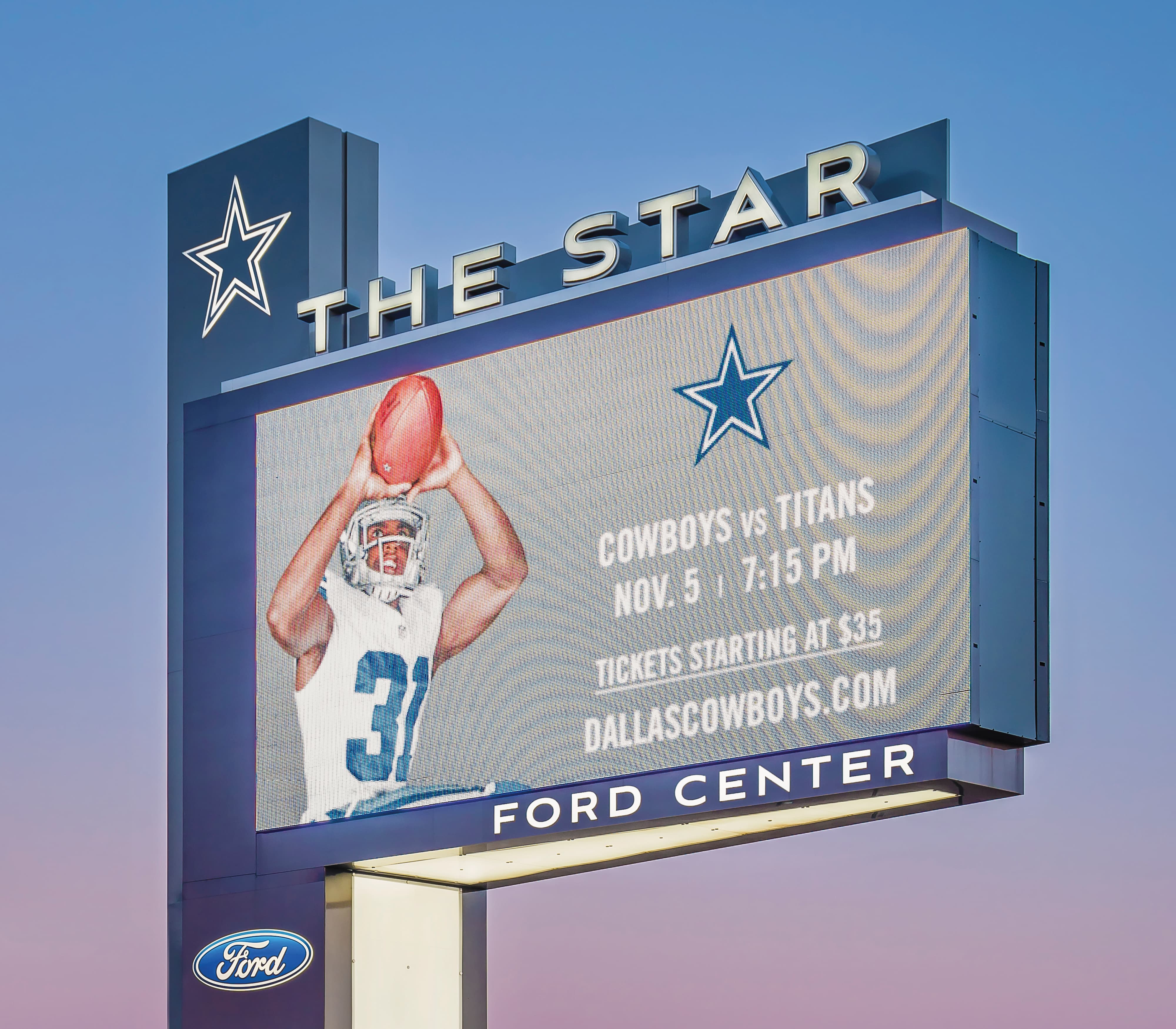 Exterior digital LED pylon sign for The Star in Frisco, Texas, featuring the Dallas Cowboys star logo, Ford Center branding, and dynamic event messaging — part of a master sign program and digital integration solution designed by RSM Design for a sports and entertainment destination.