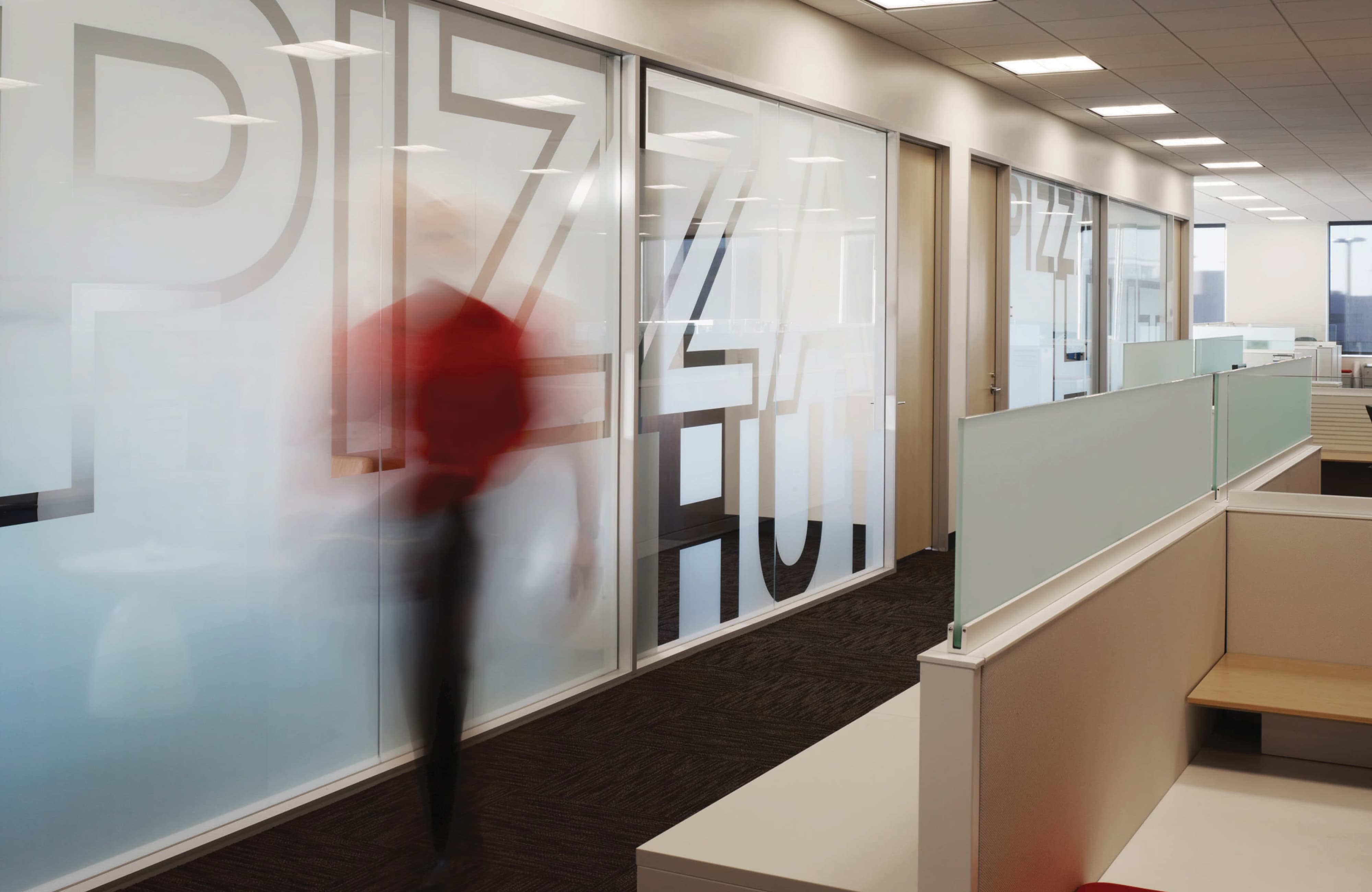 Corporate workplace interior featuring branded environmental graphics applied to glass walls, illustrating experiential graphic design, branded environments, and placemaking within a modern office and workplace environment.