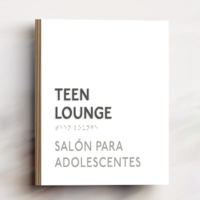 Bilingual wall sign reading 'Teen Lounge' and 'Salón para Adolescentes' with braille text, mounted on a wood-edged white panel