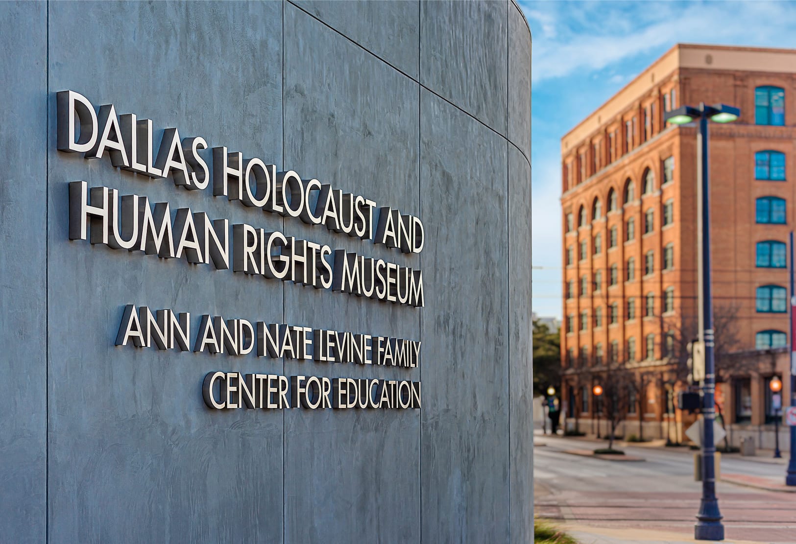 Angled view of Dallas Holocaust and Human Rights Museum dimensional signage with historic Dallas building beyond - exterior identity design by RSM Design